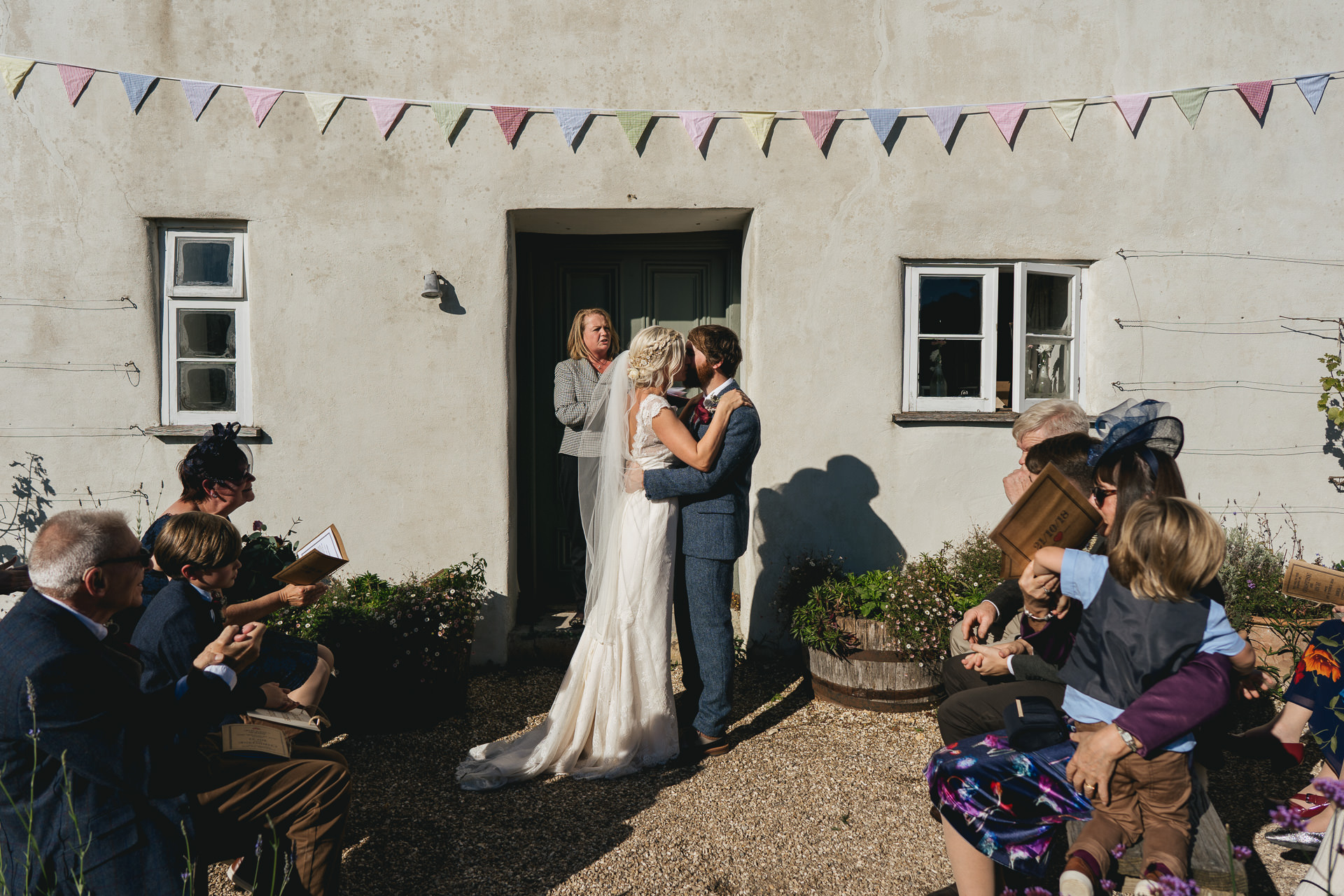 Bride and groom having first kiss outside farmhouse