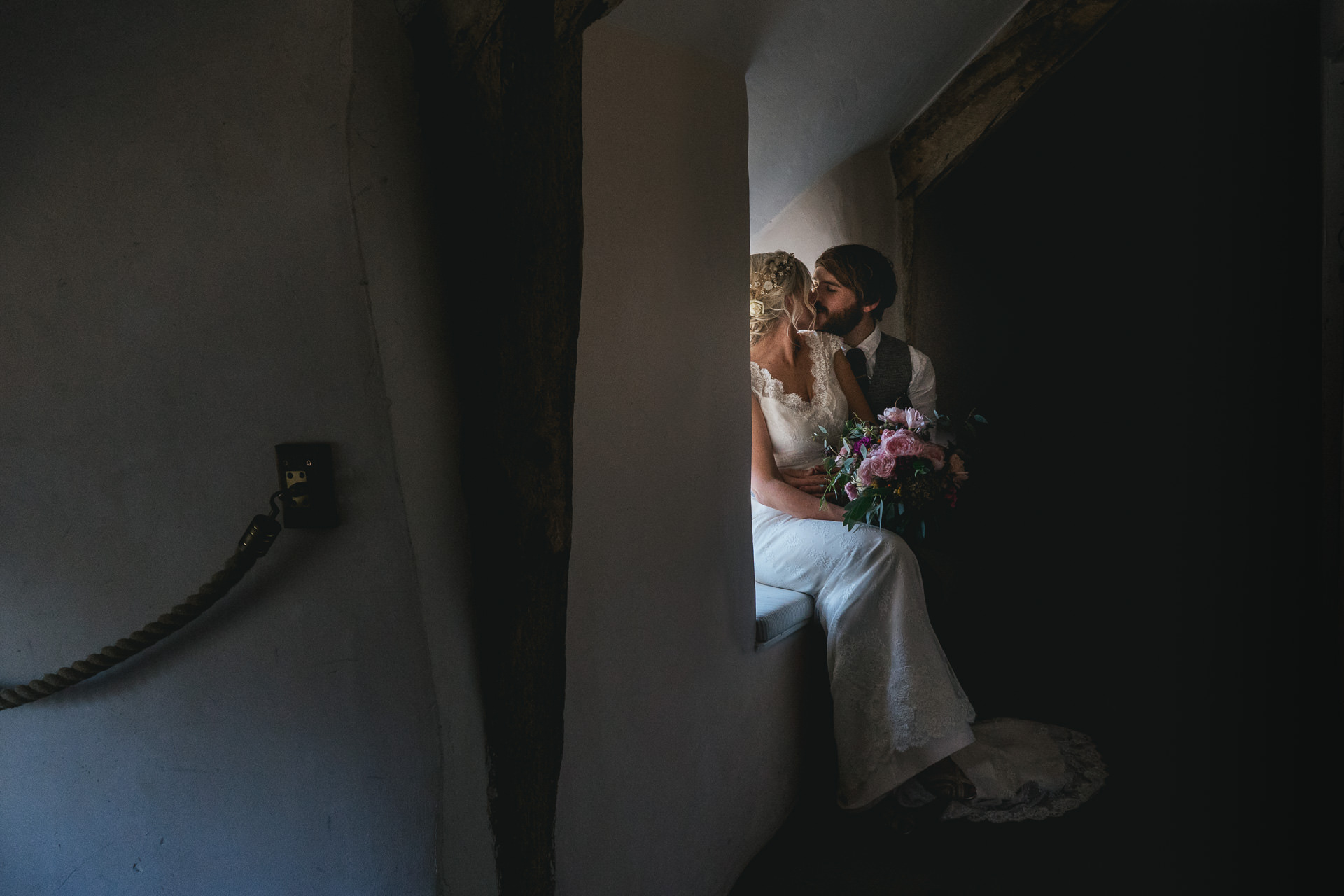 Bride and groom kissing on a windowsill inside River Cottage farmhouse