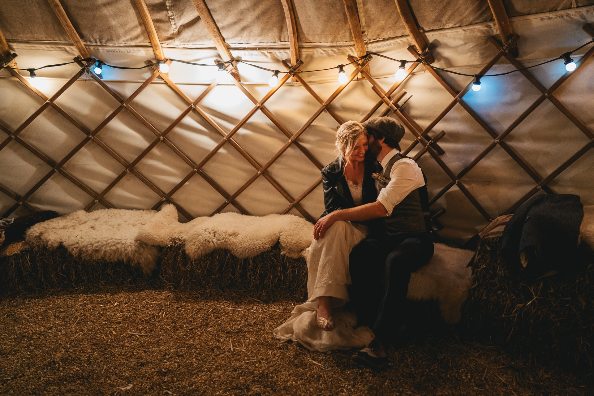 Bride in leather jacket smiling with groom in a yurt