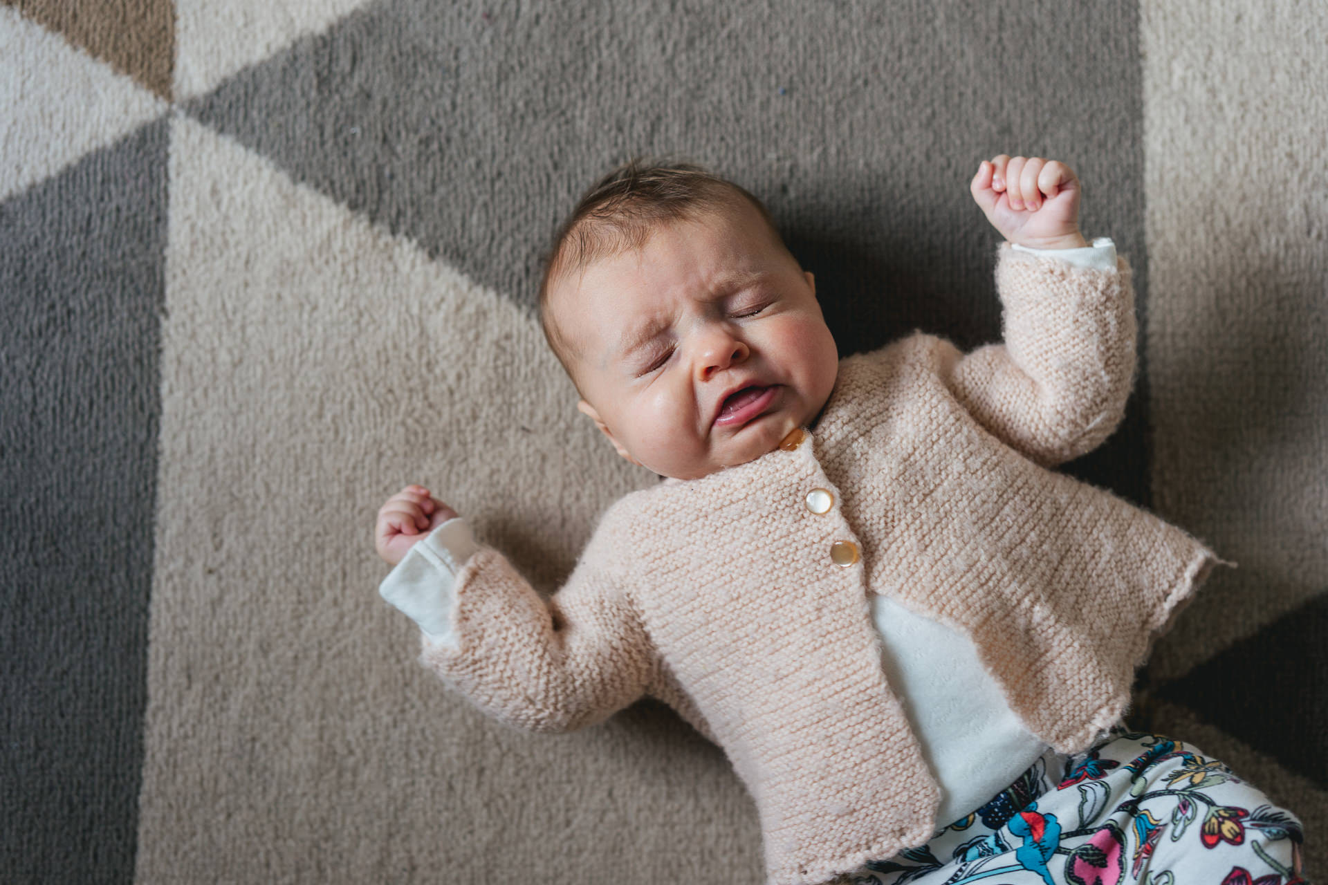 A baby sneezing on a rug