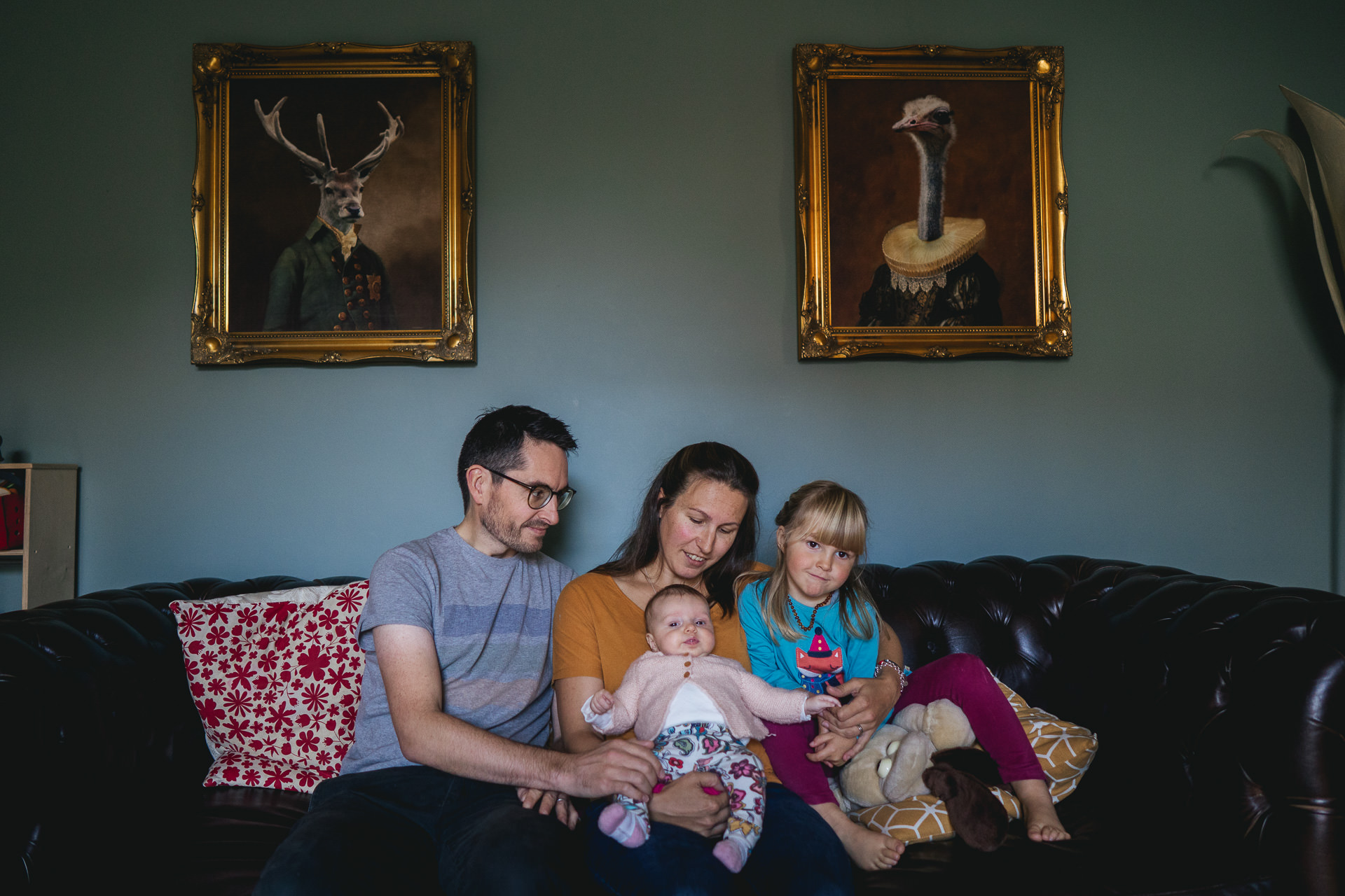 Exeter family photography: a family sitting together on a sofa with pictures hanging above
