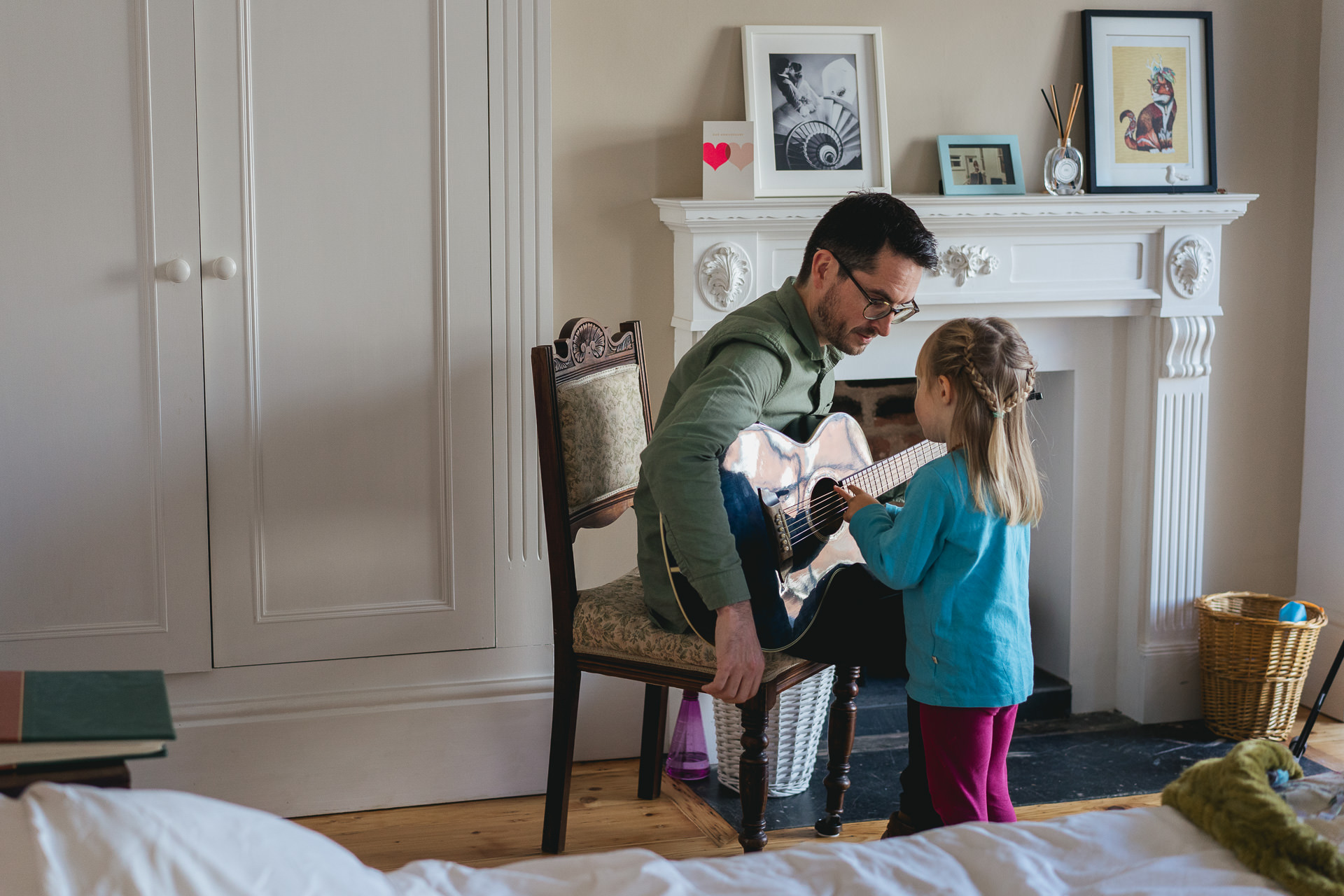 A dad playing guitar with a young daughter