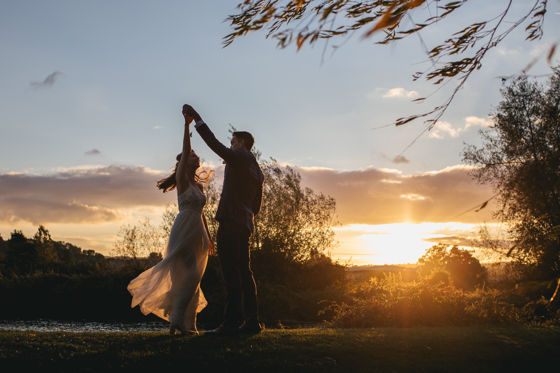 Bride and groom twirling around with sunset behind