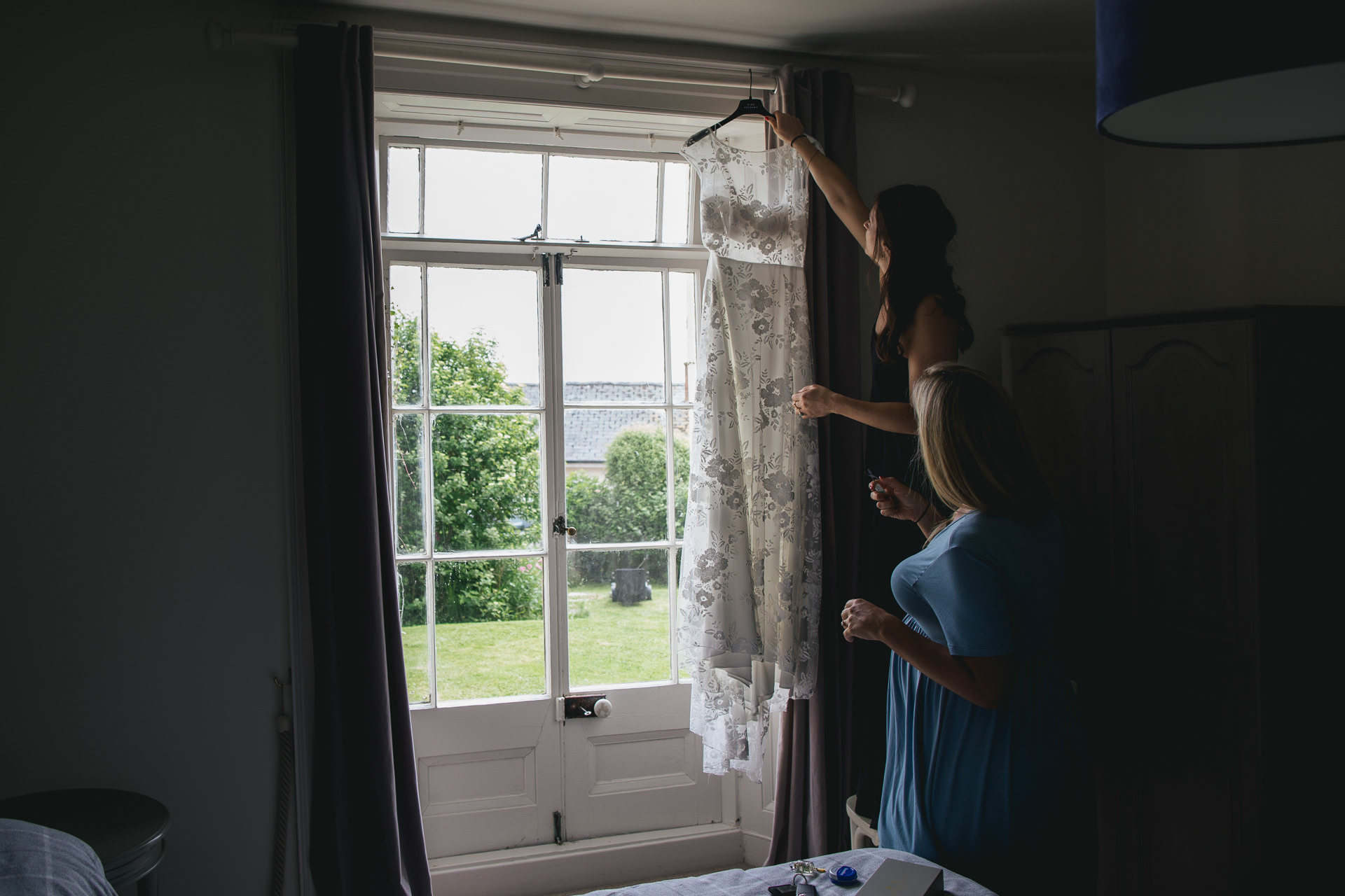 Woman hanging up a wedding dress in a window