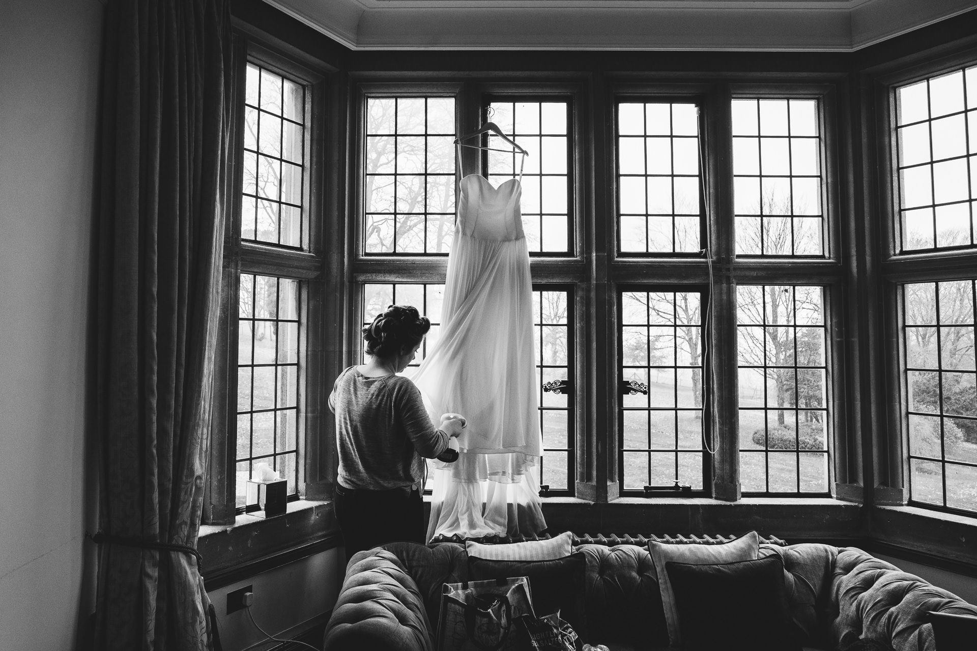 Bride-to-be steaming a wedding dress hanging in a window