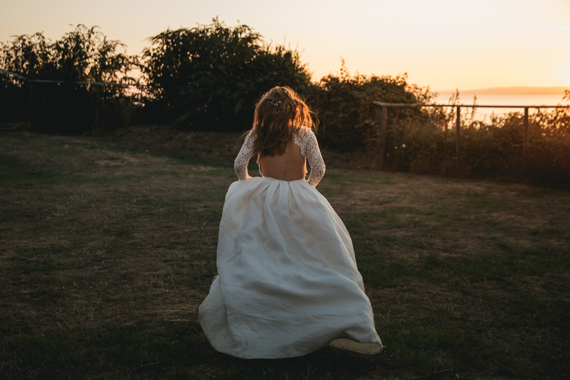 Bride in Rime Arodaky dress running across lawn in sunset