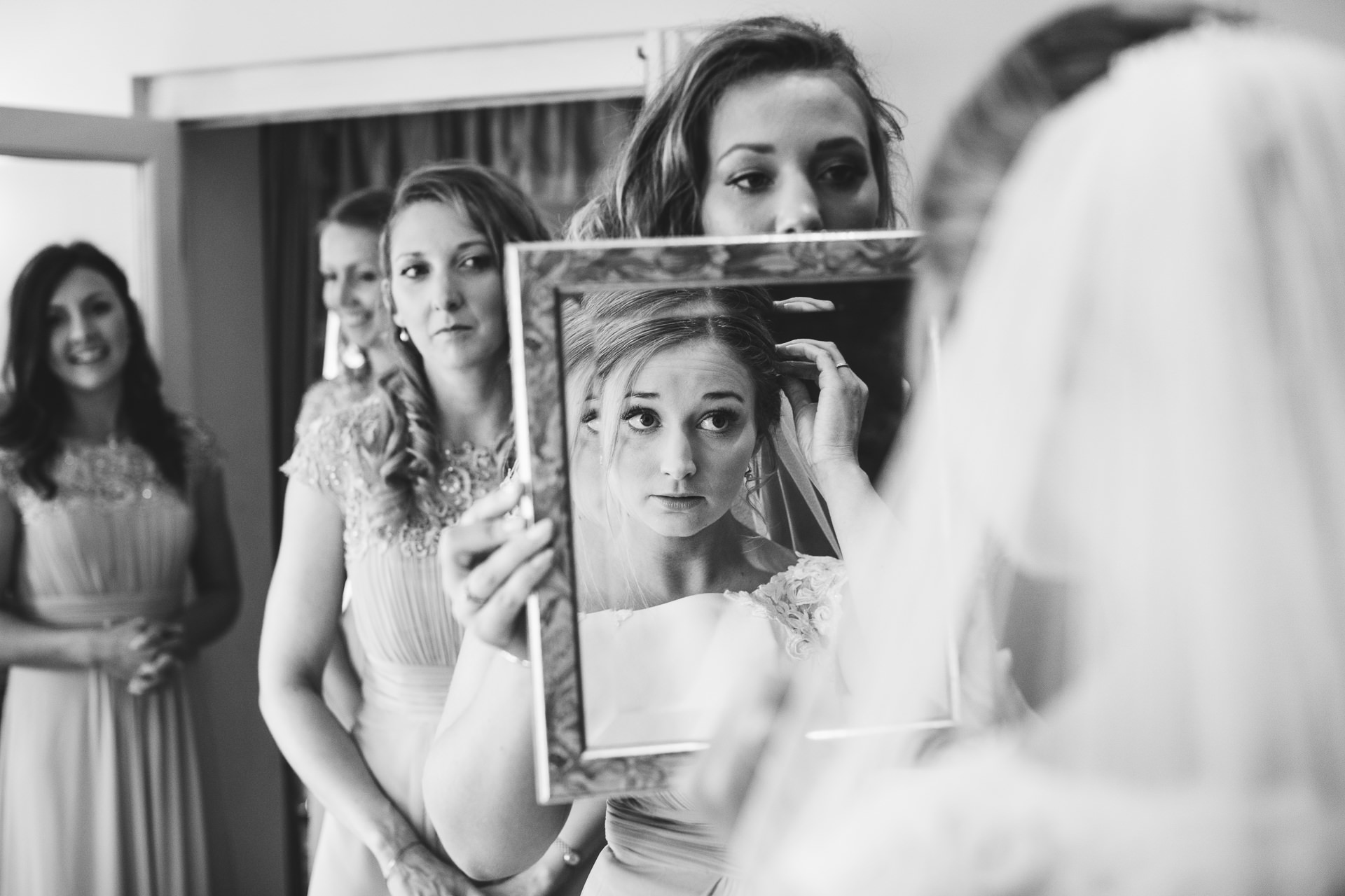 Bride-to-be looking in mirror with bridesmaids behind