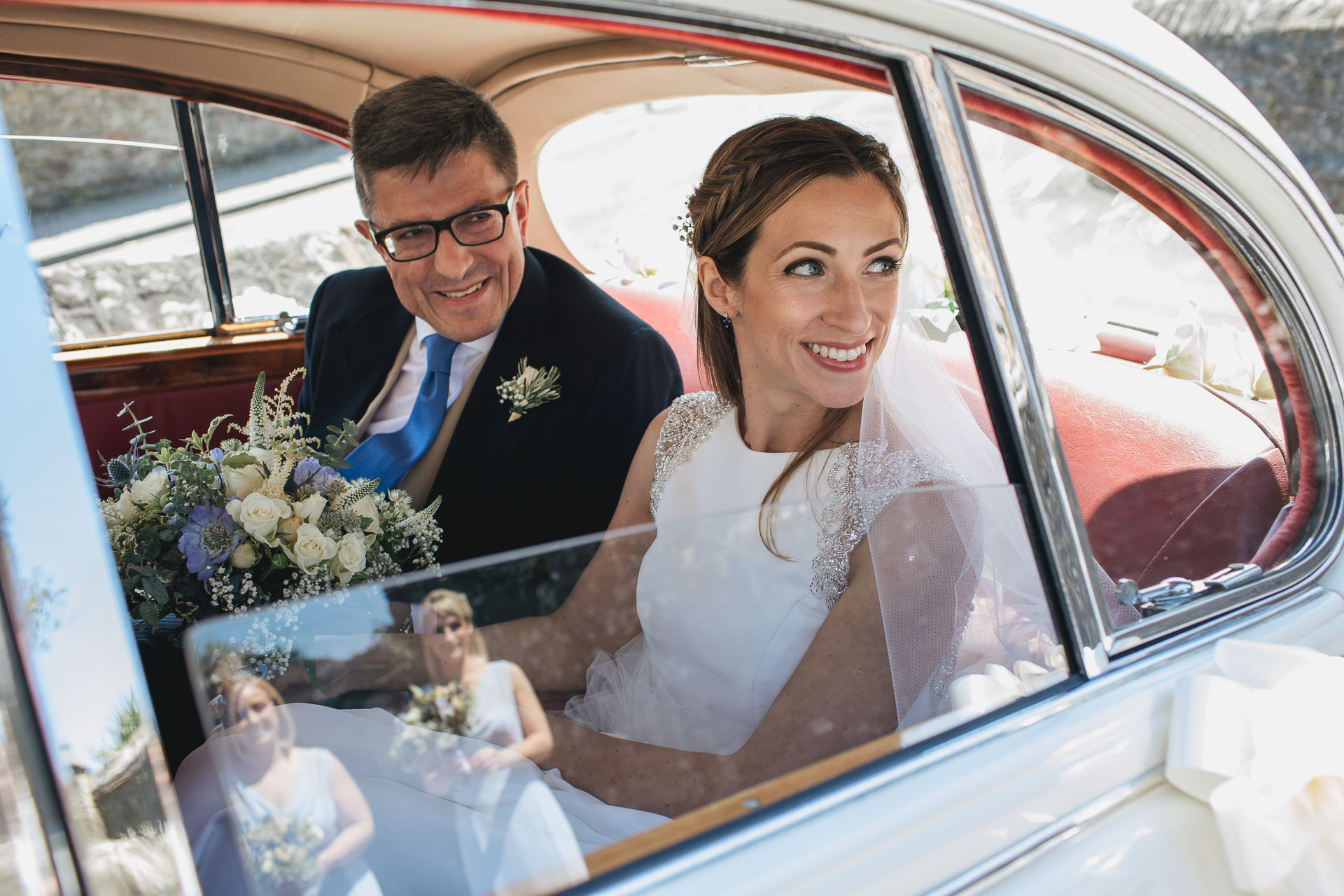 A bride arriving in a car with her father