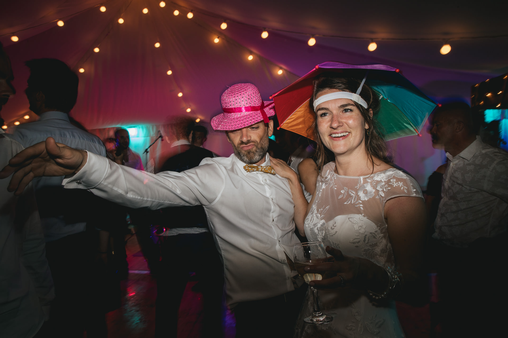 Bride and groom wearing silly hats on a dancefloor