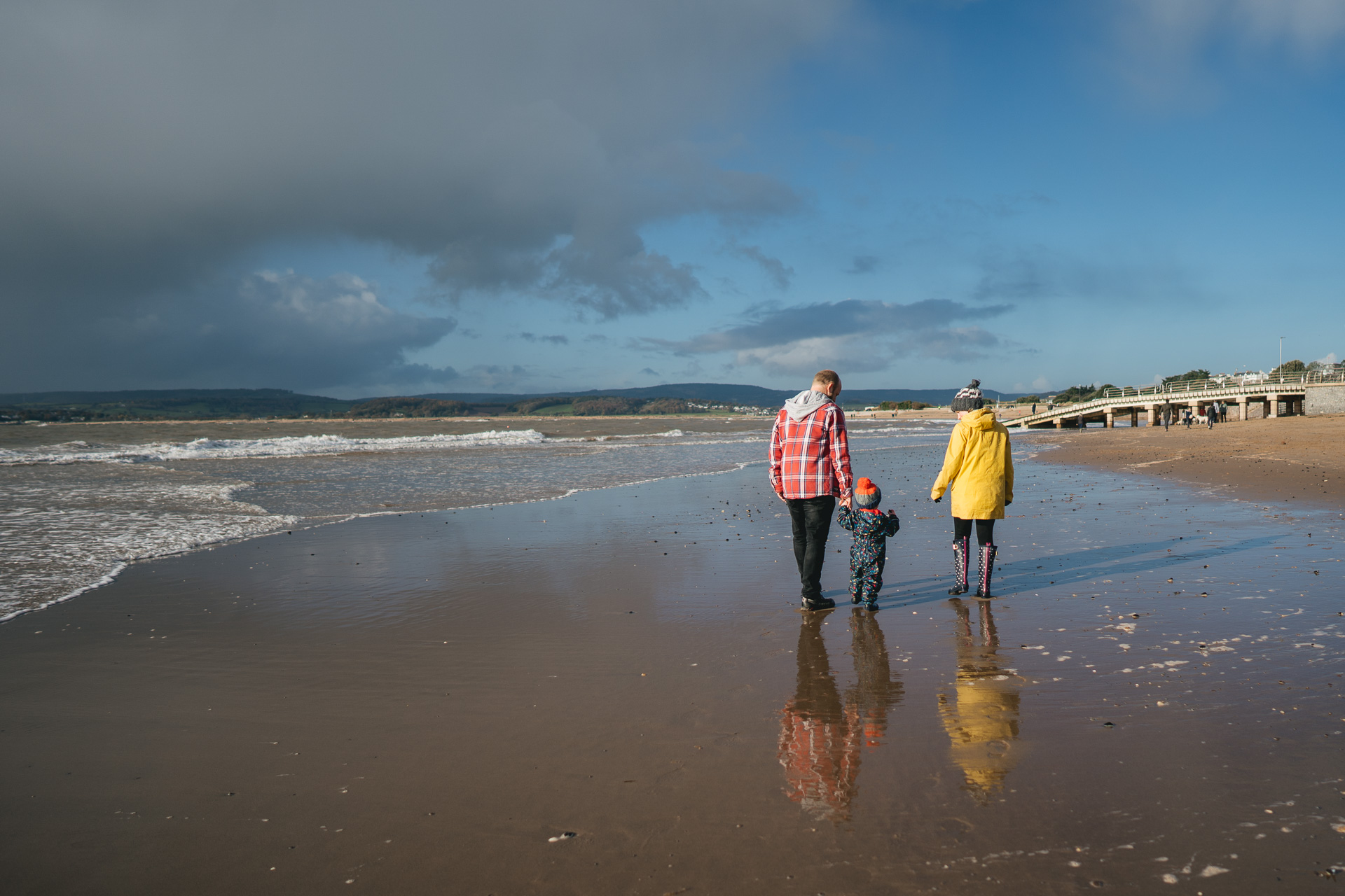 A man, woman and young child walking on a beach together