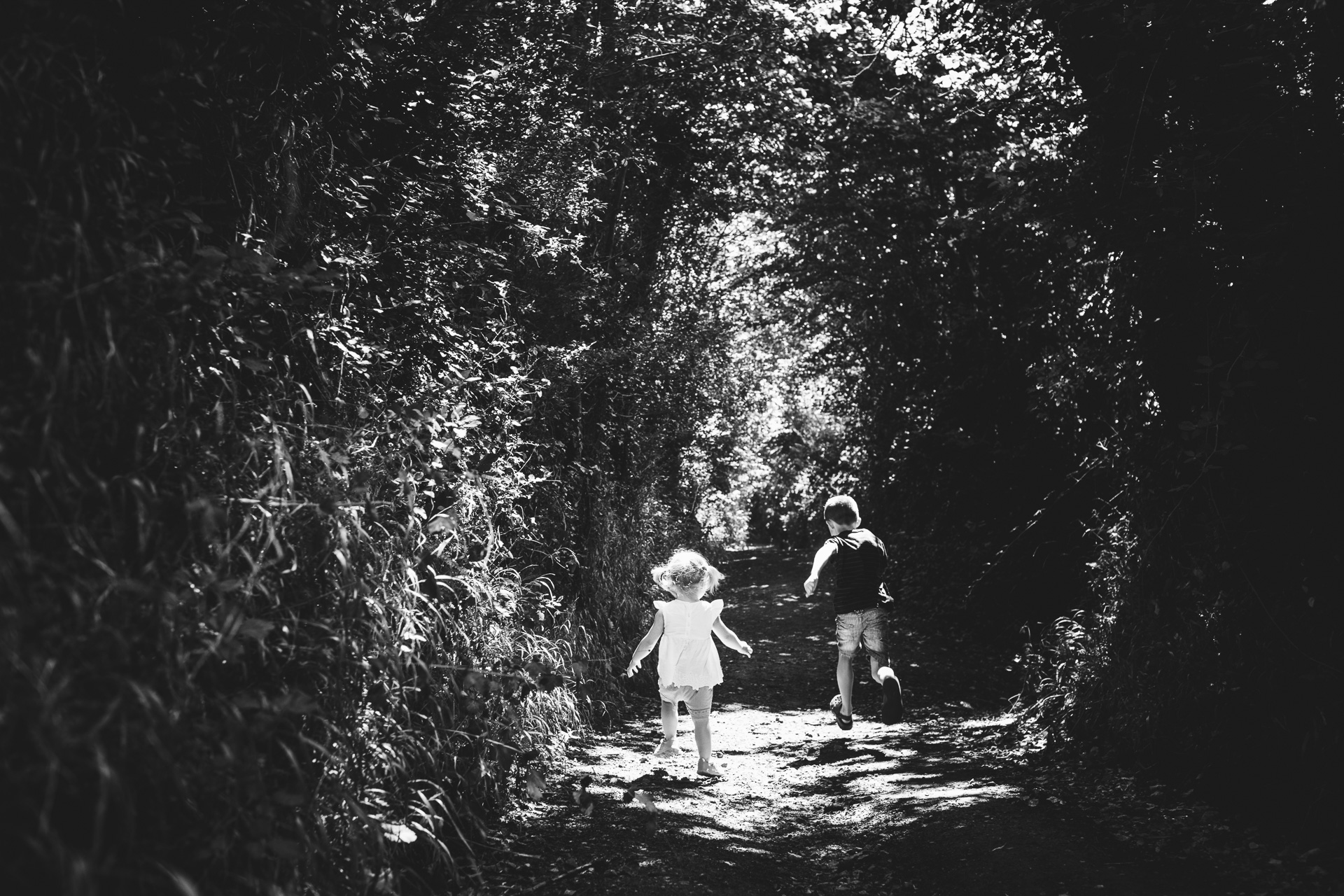 Two children running through a tunnel of trees