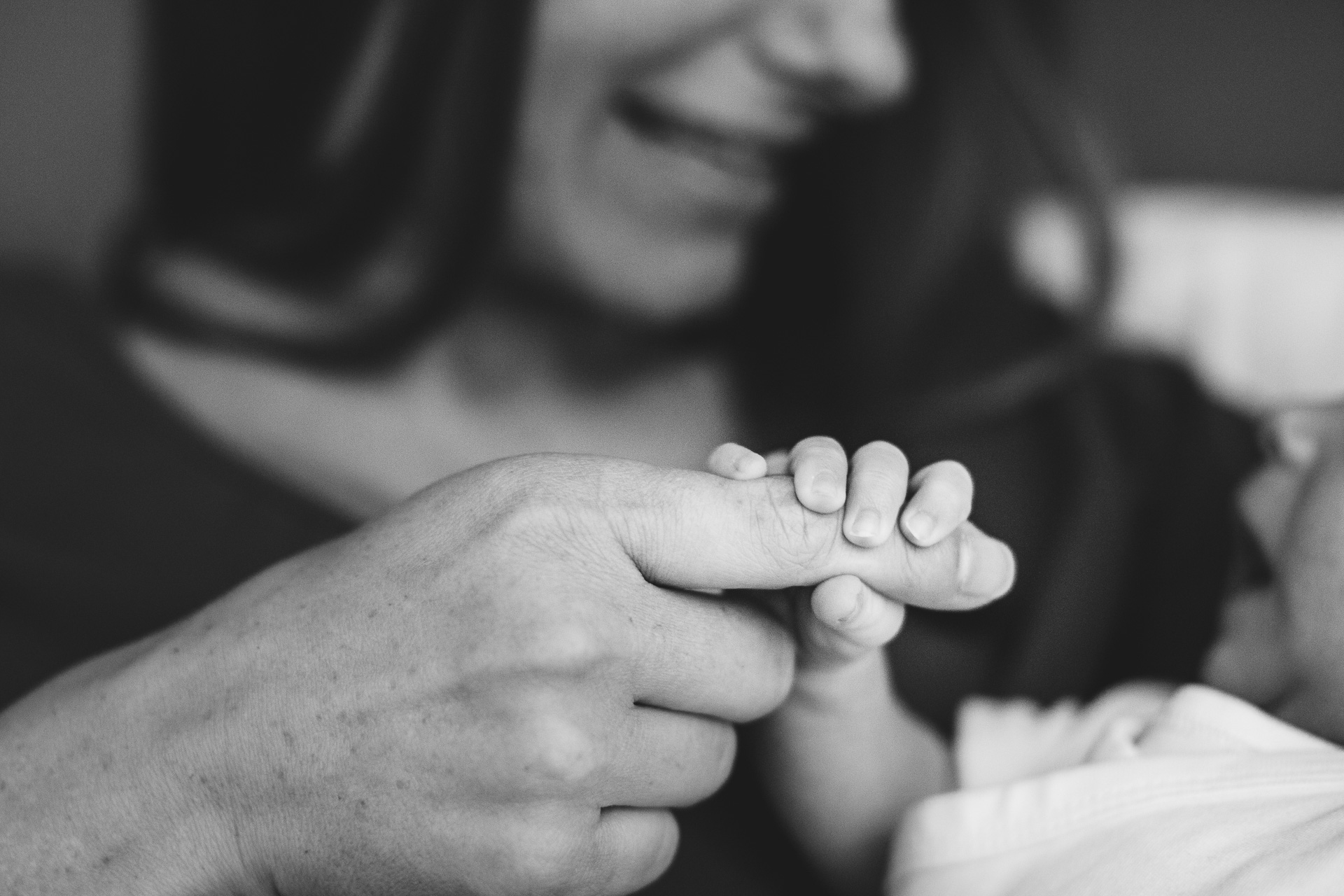 A baby's hand, holding his mother's finger