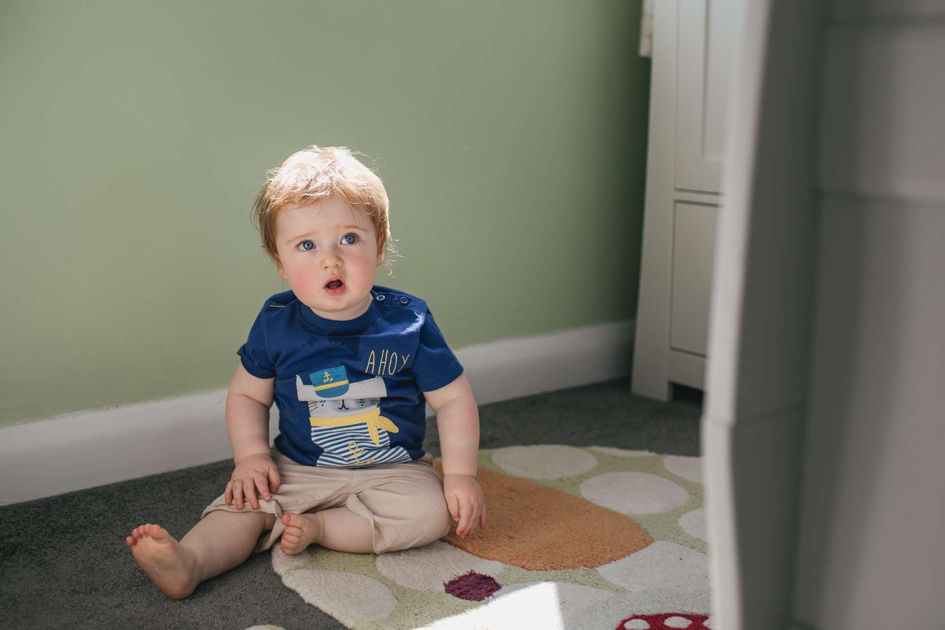 A toddler boy sitting in a nursery