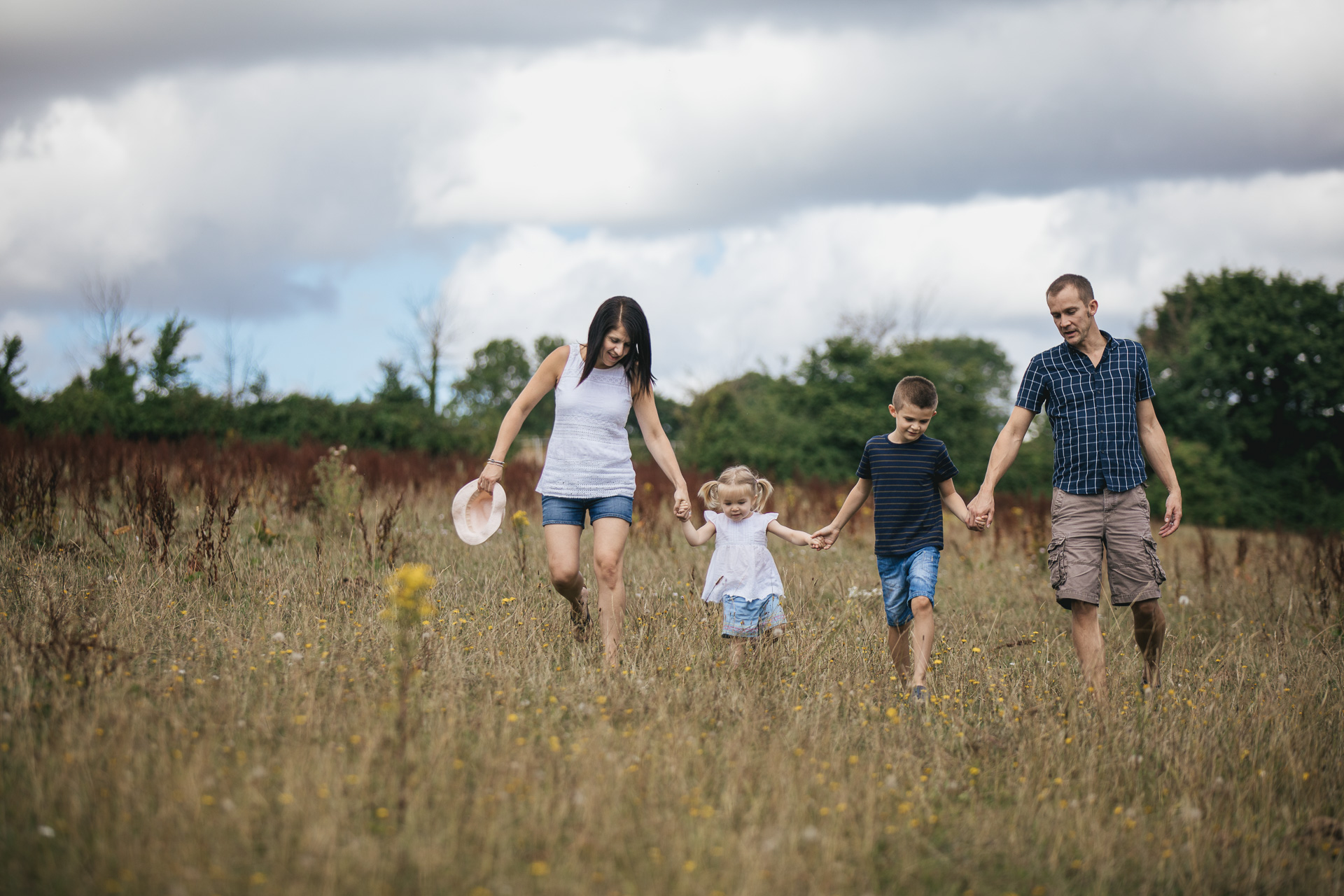 Mother, father and two children walking through a field together