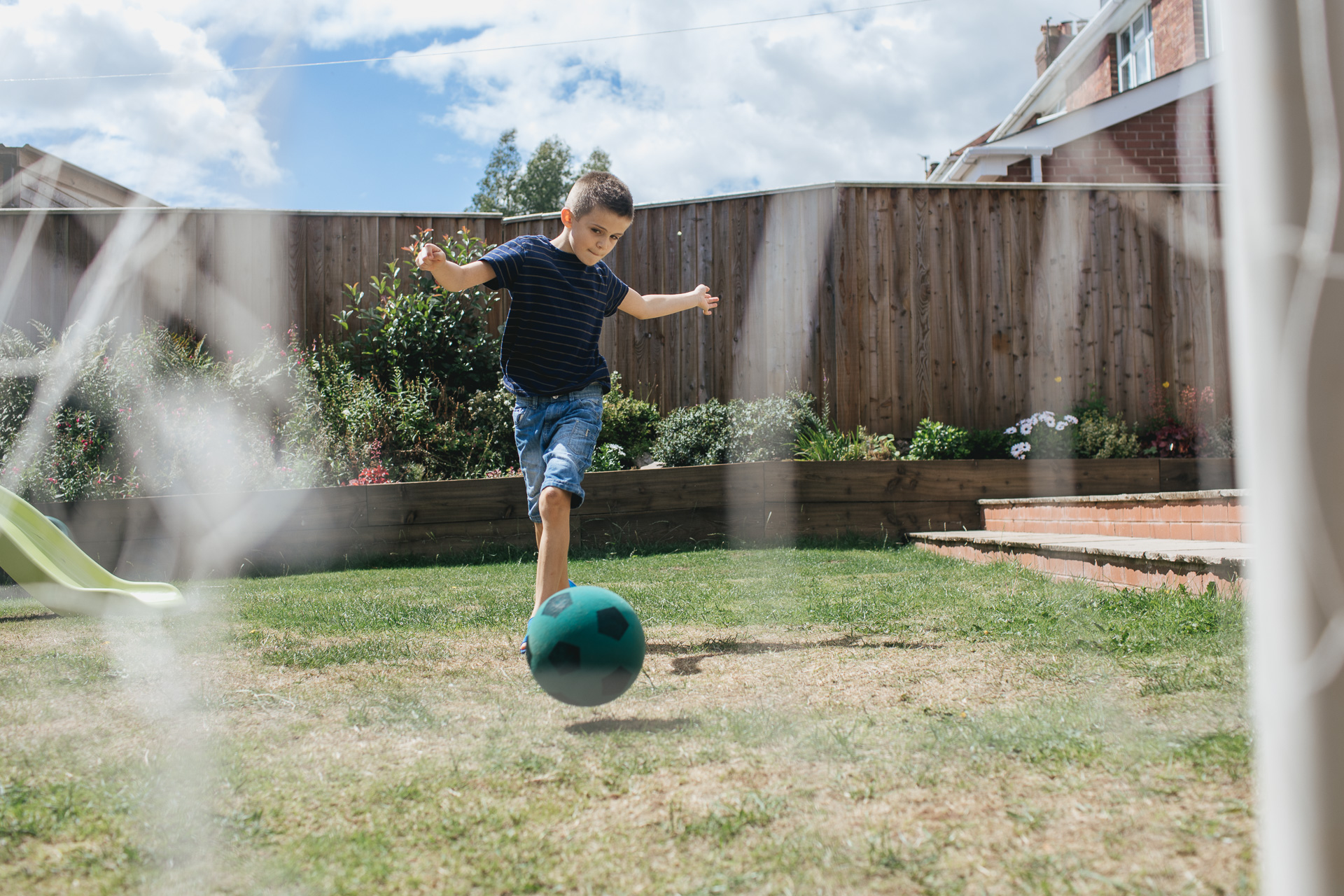A boy kicking a ball into a football goal