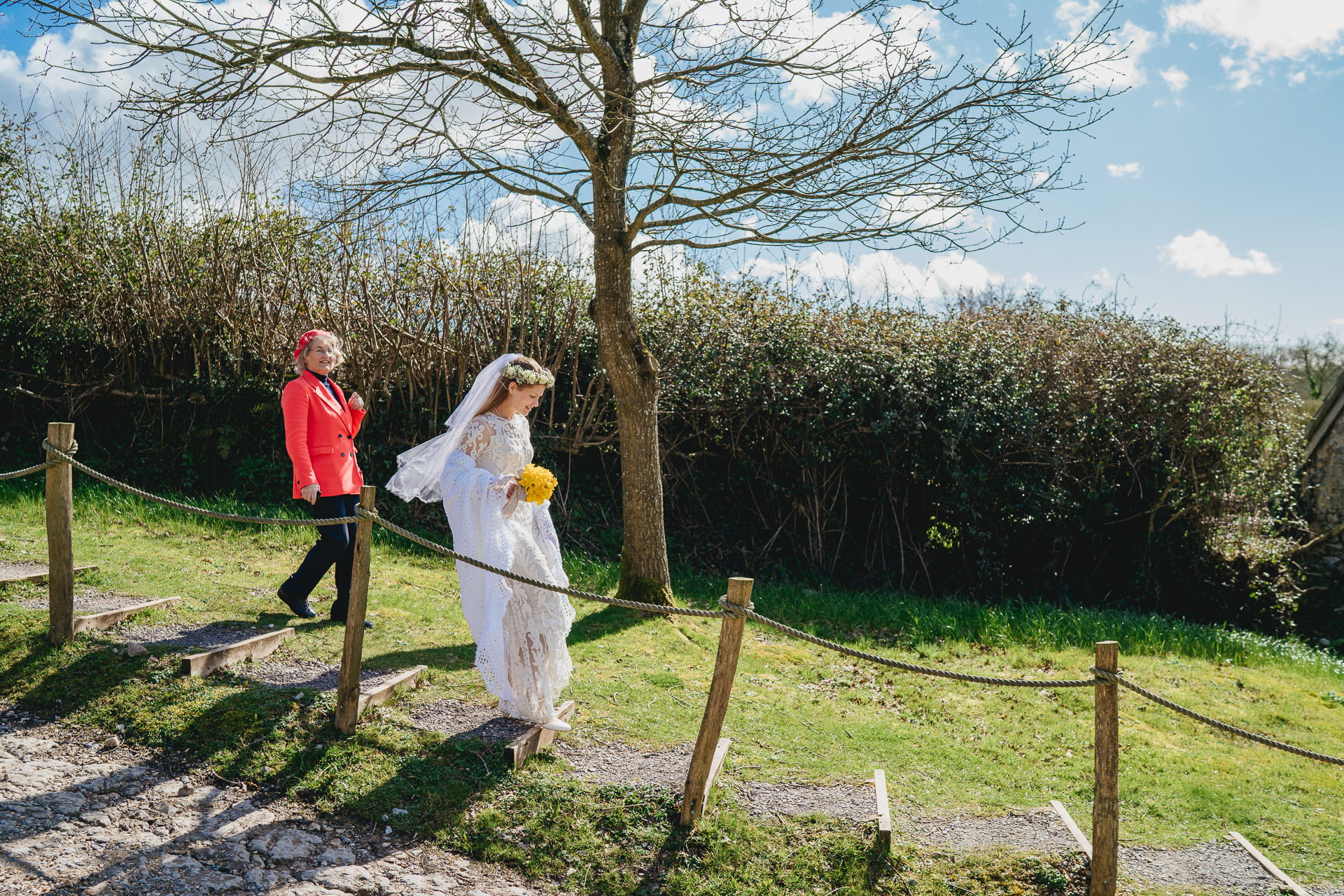 A bride walking down a path in the sunshine