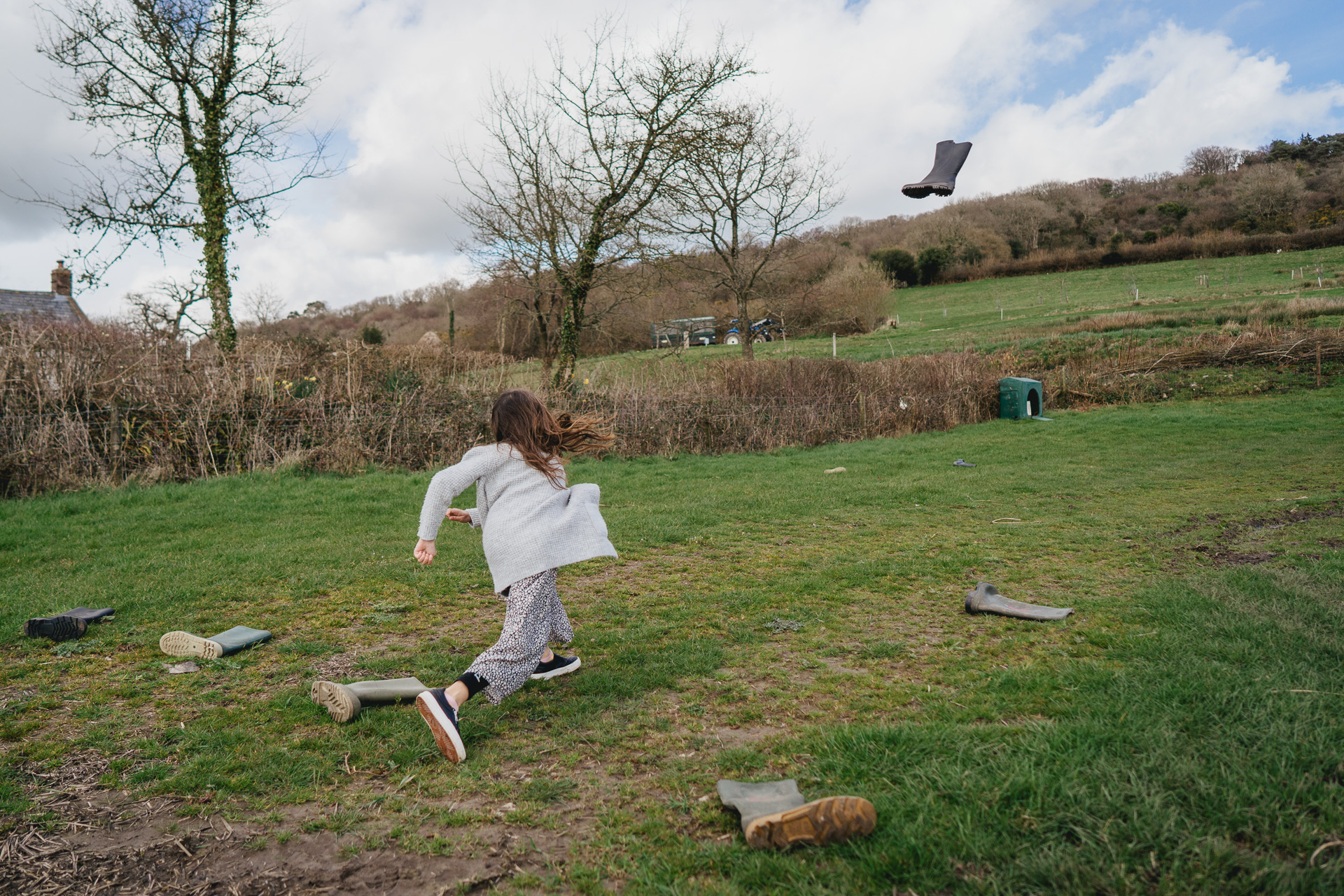A young girl throwing a welly in a field