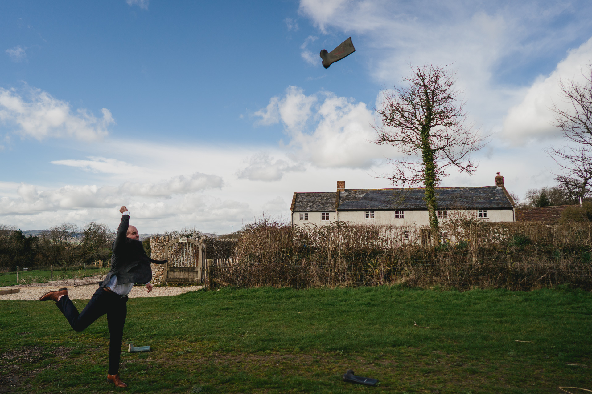A wedding guest throwing a welly in front of River Cottage farmhouse