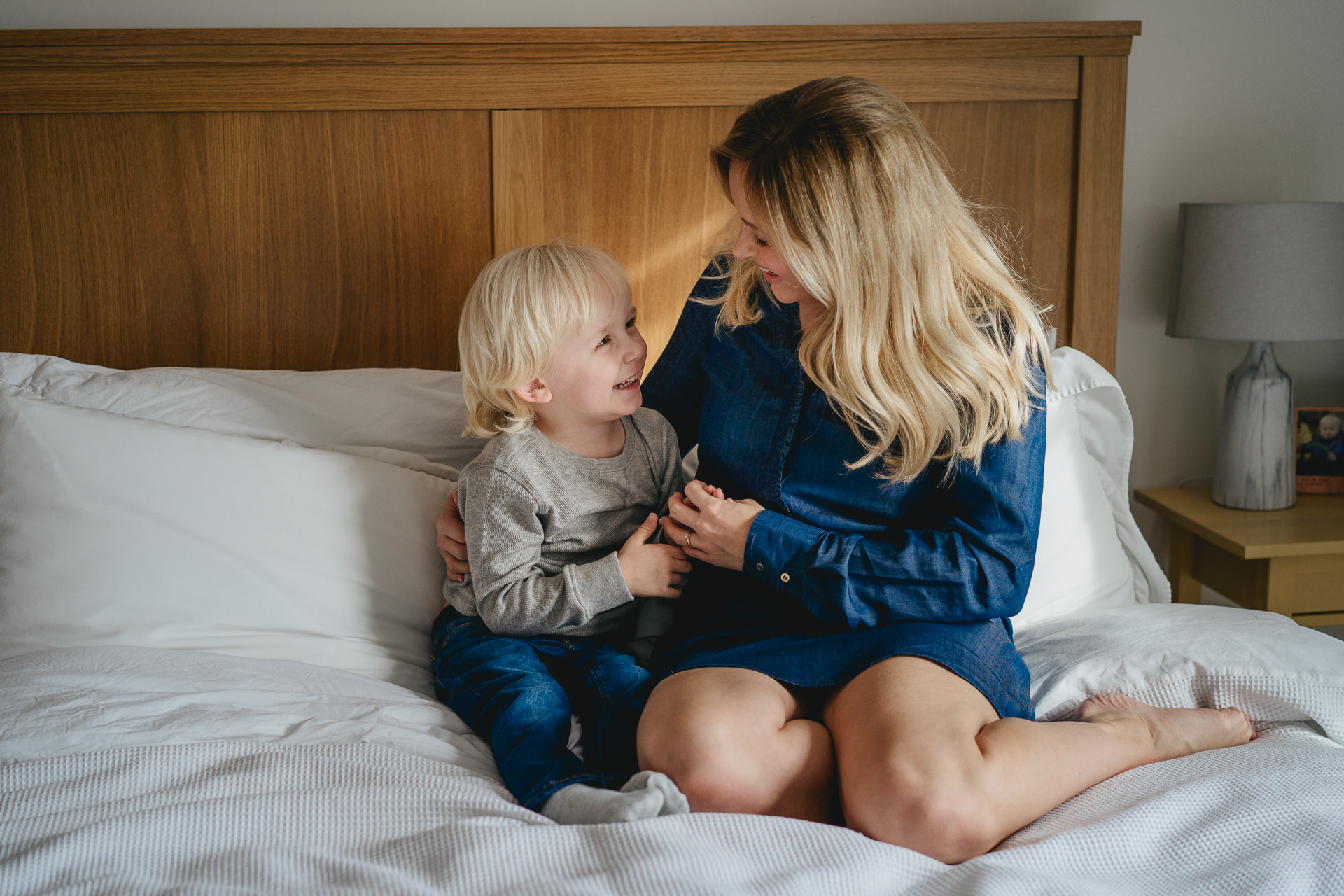 Dorset family photography - a mother and her young son laughing together on a bed