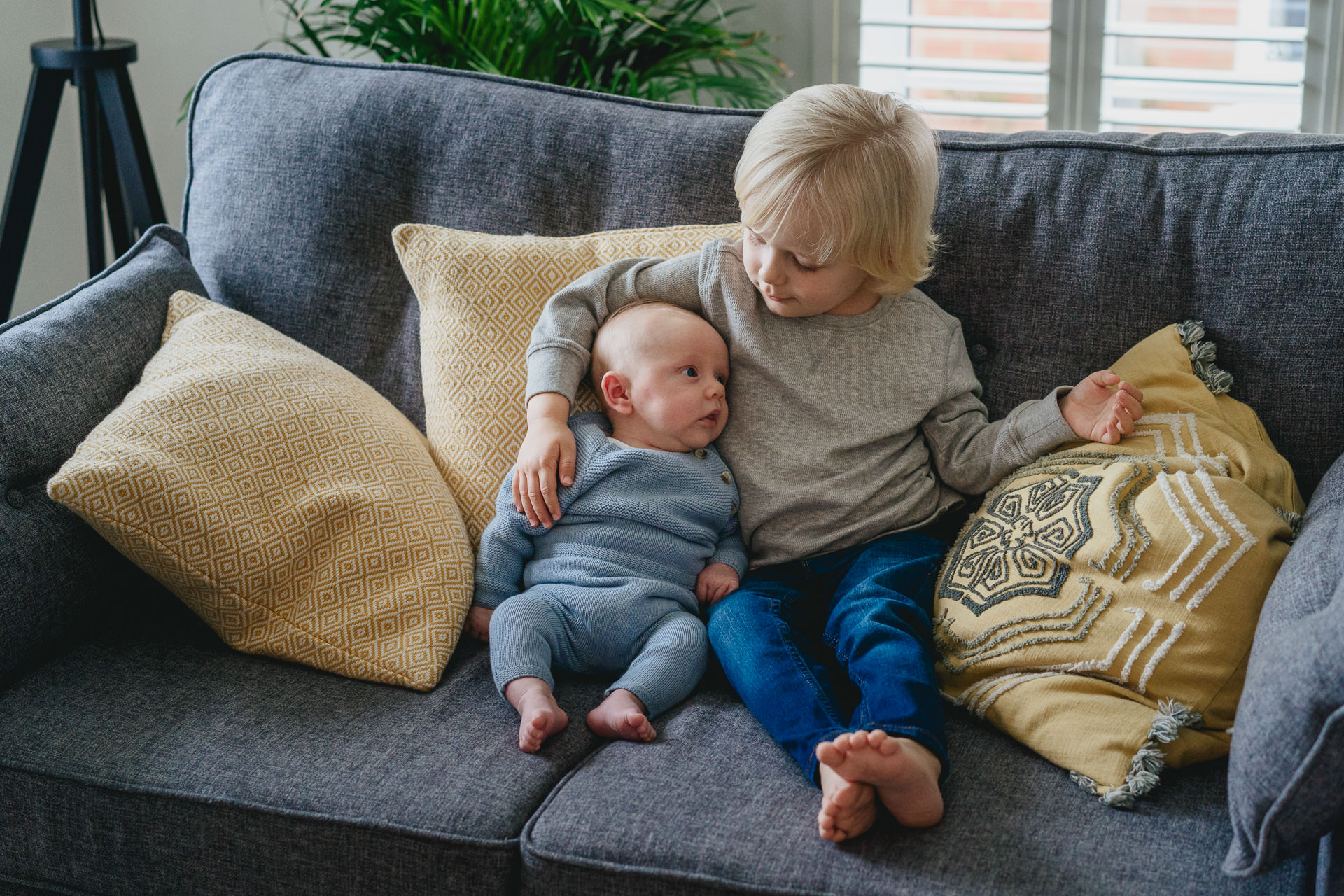 Young boy cuddling his baby brother on a sofa