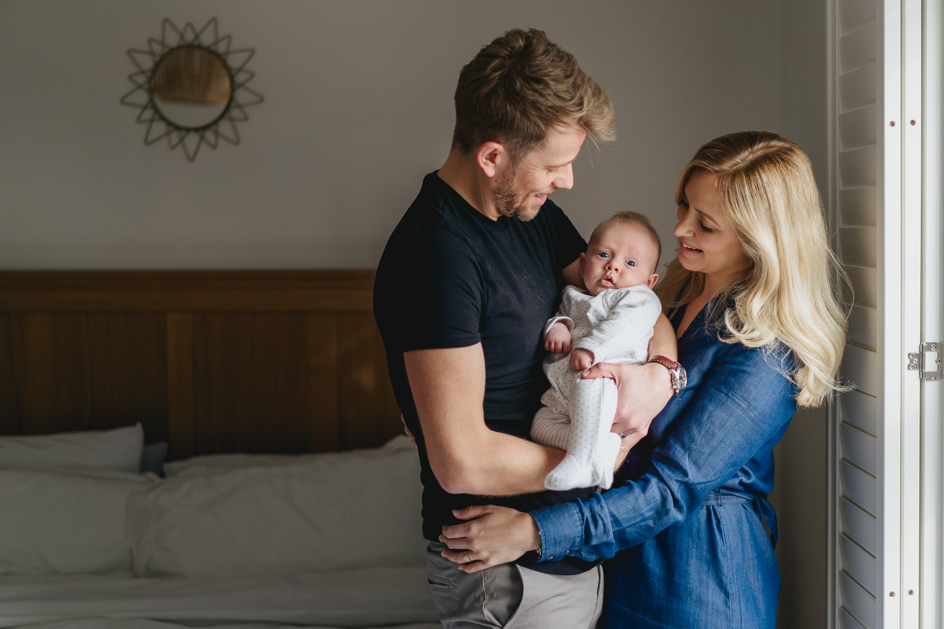Mother and father cuddling a small baby together during a Dorset family photography shoot at home