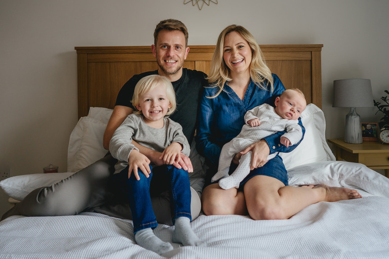 Dorset family photography at home - a portrait of a family of four on a bed together 