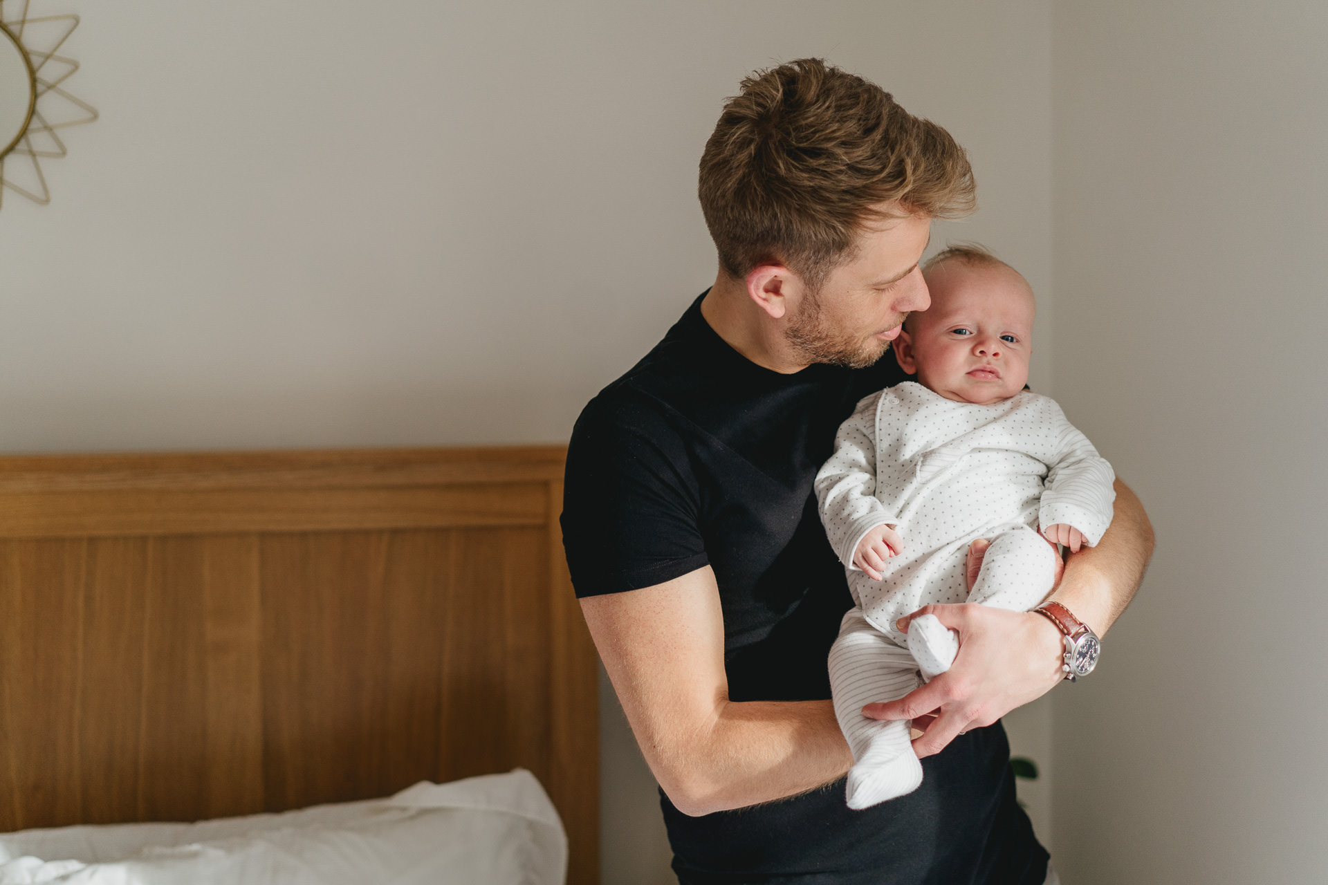 Dorset family photography: Dad kissing his baby son in a bedroom
