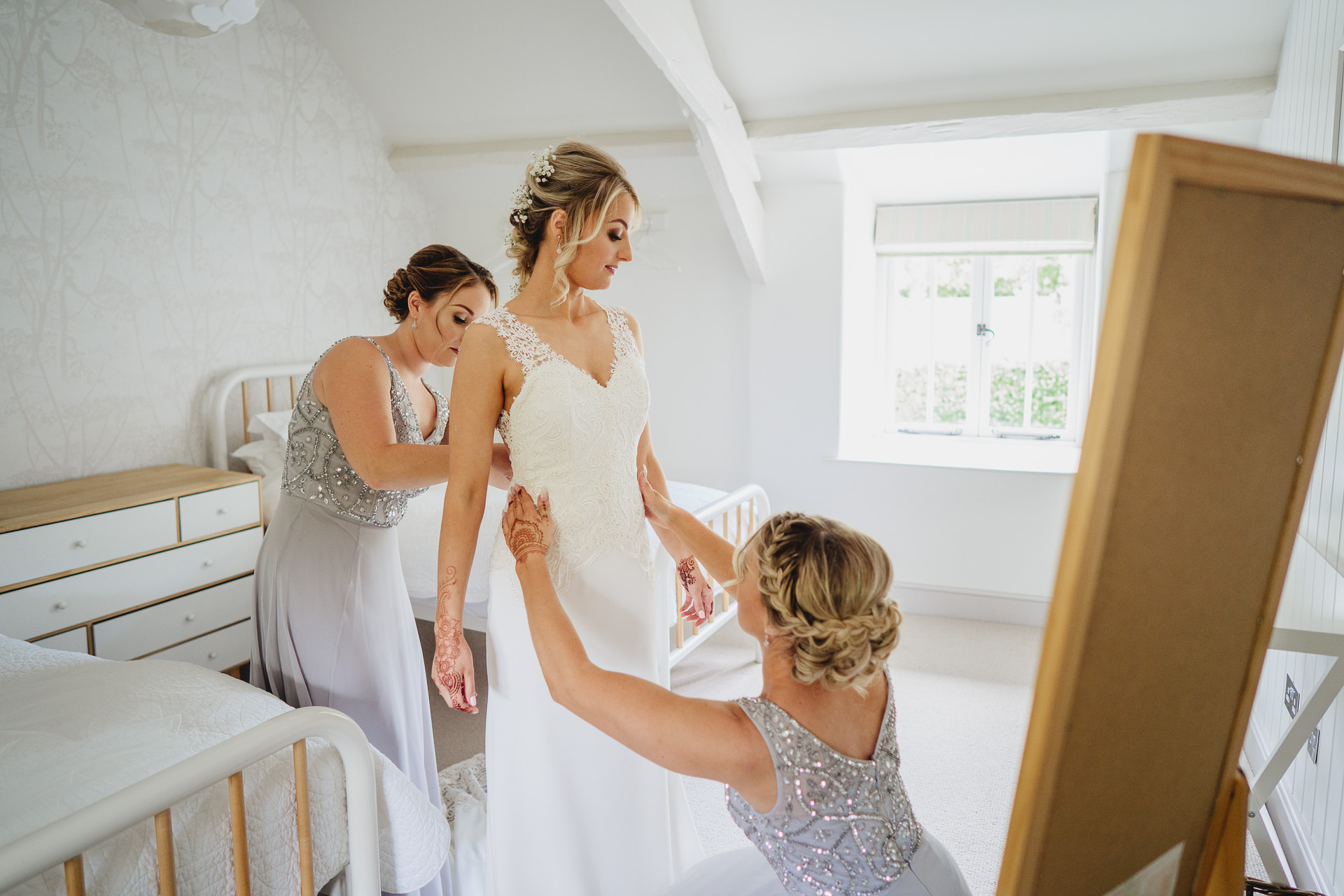 Bride putting on her wedding dress with bridesmaids