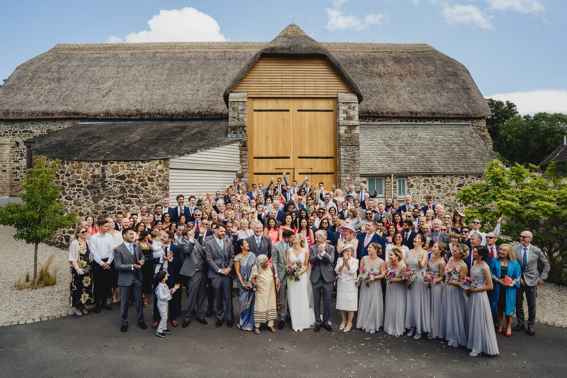 Large wedding group photo in front of The Great Barn, Devon
