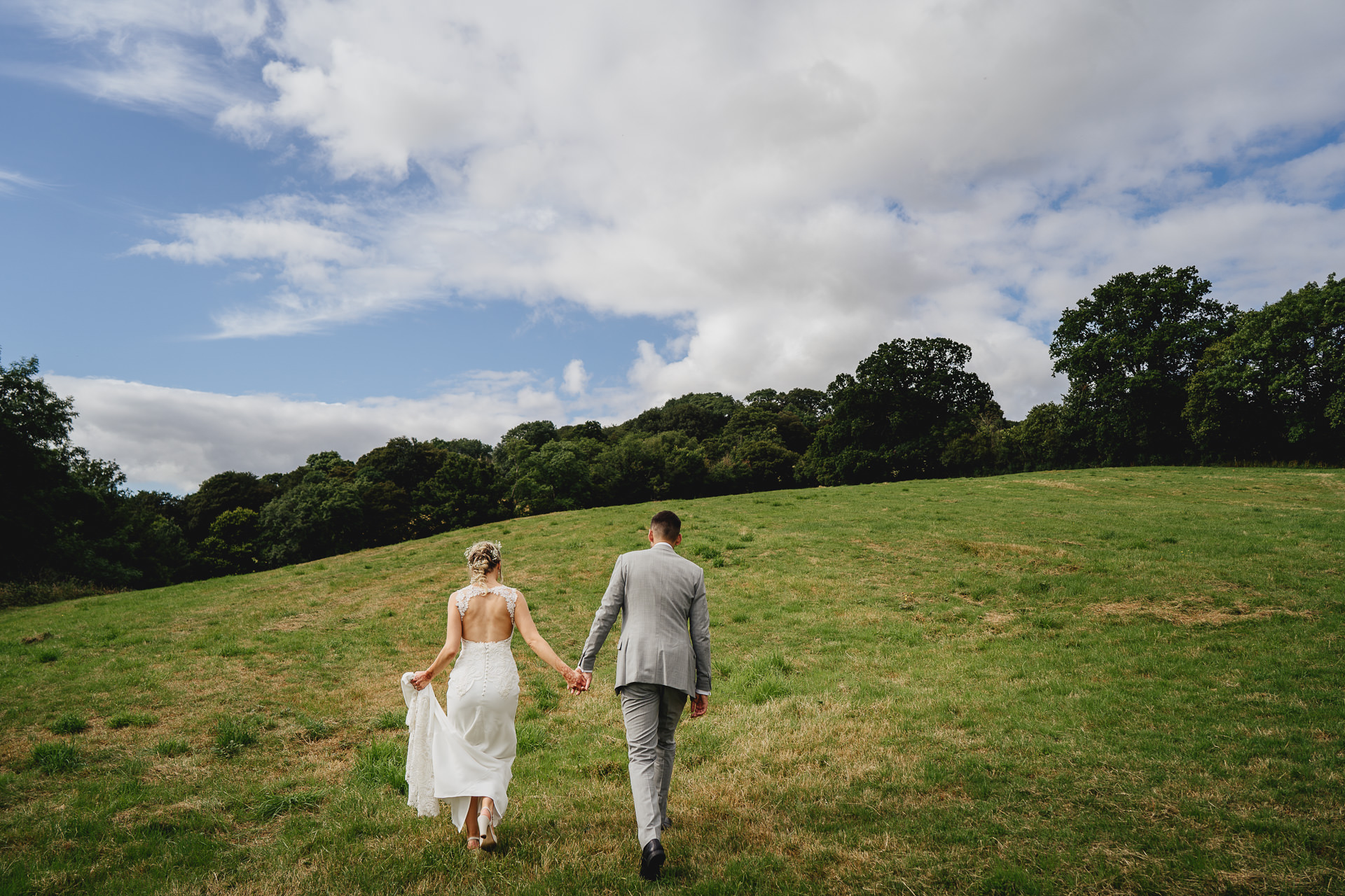 A bride and groom on hills with countryside around them