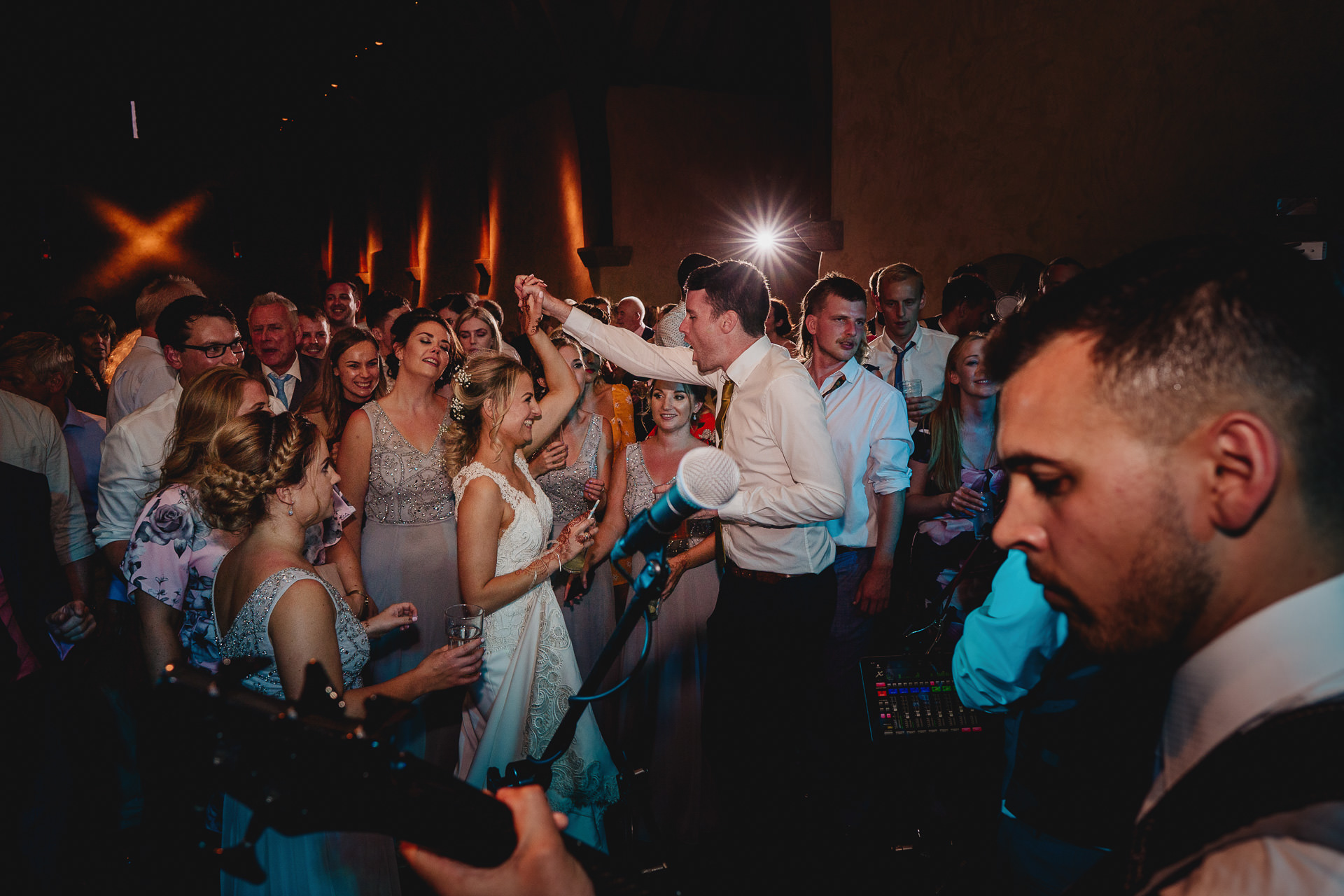 Wedding guests dancing to a band inside the barn