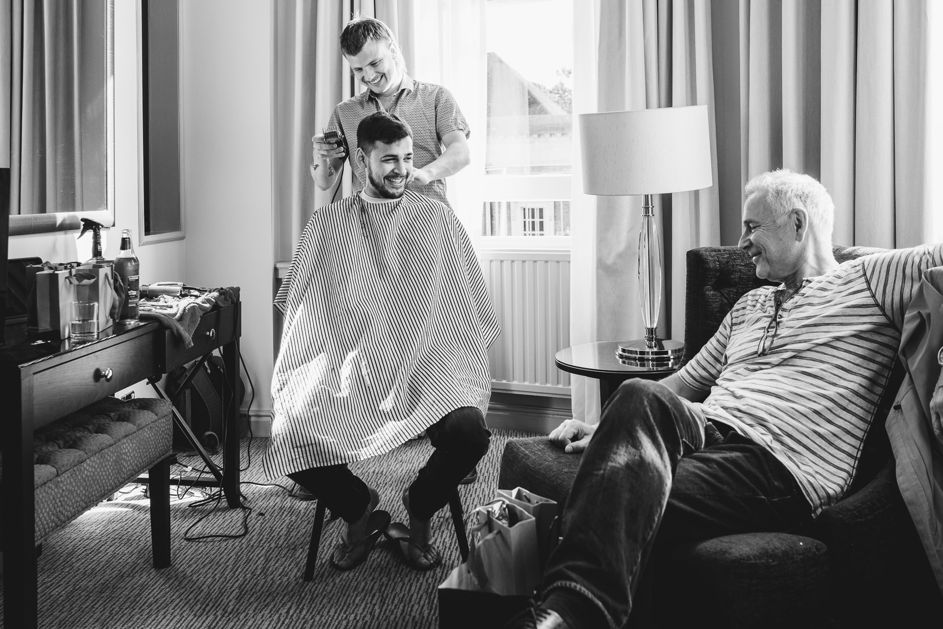 Groom having his hair cut and laughing with his father