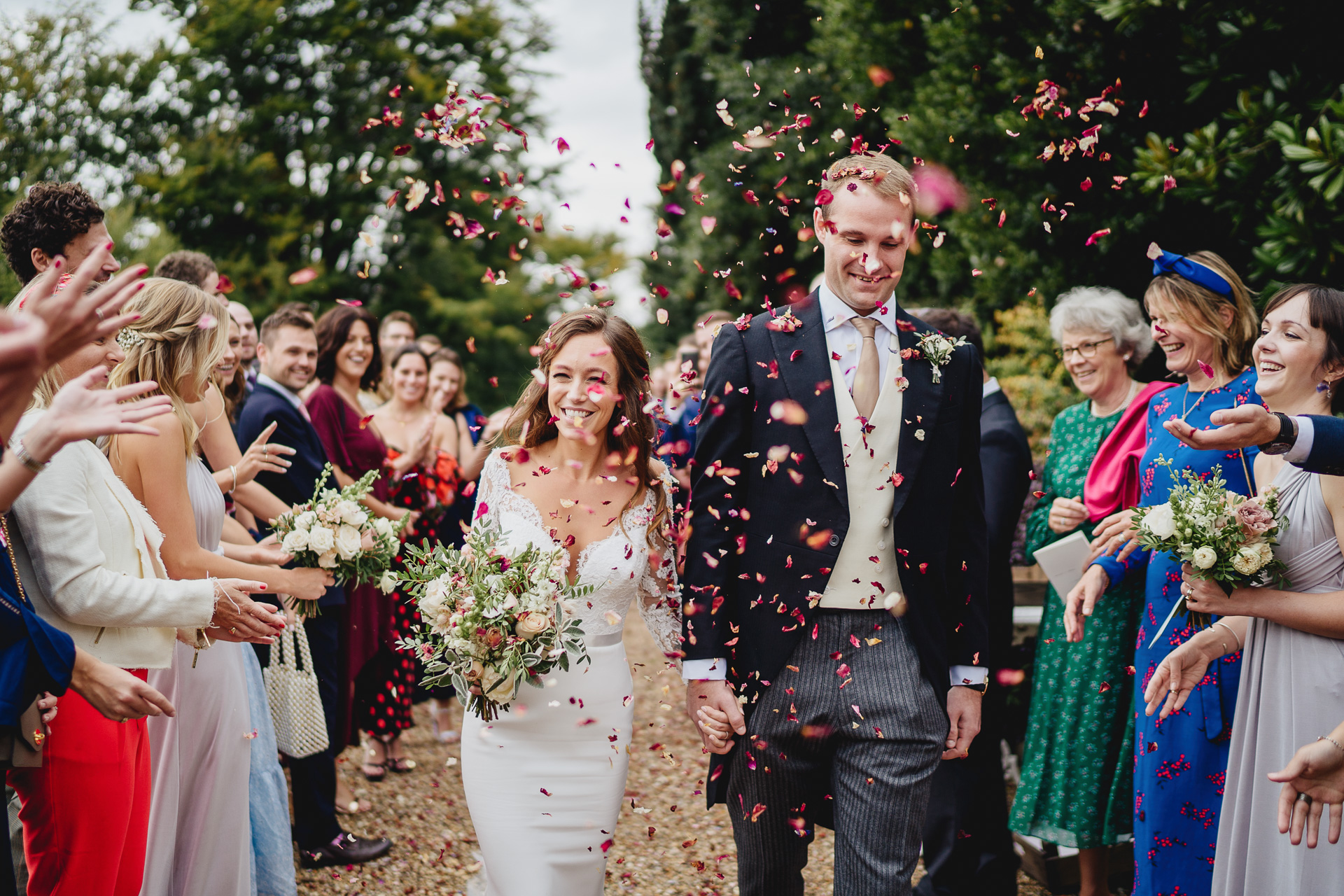 Bride and groom smiling and walking through confetti at their Pennard House wedding