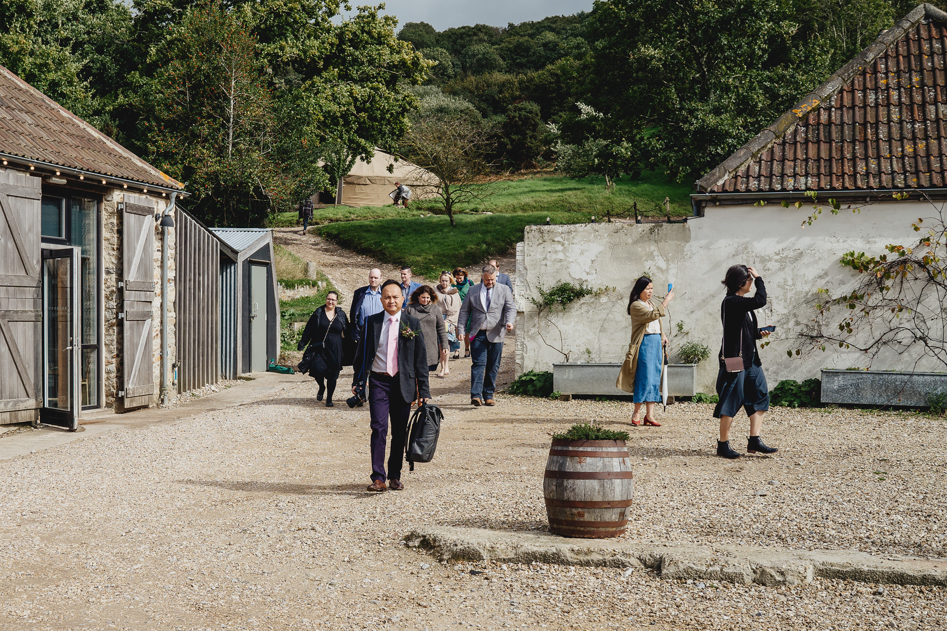wedding guests walking across a courtyard, arriving for an outdoor autumn wedding ceremony