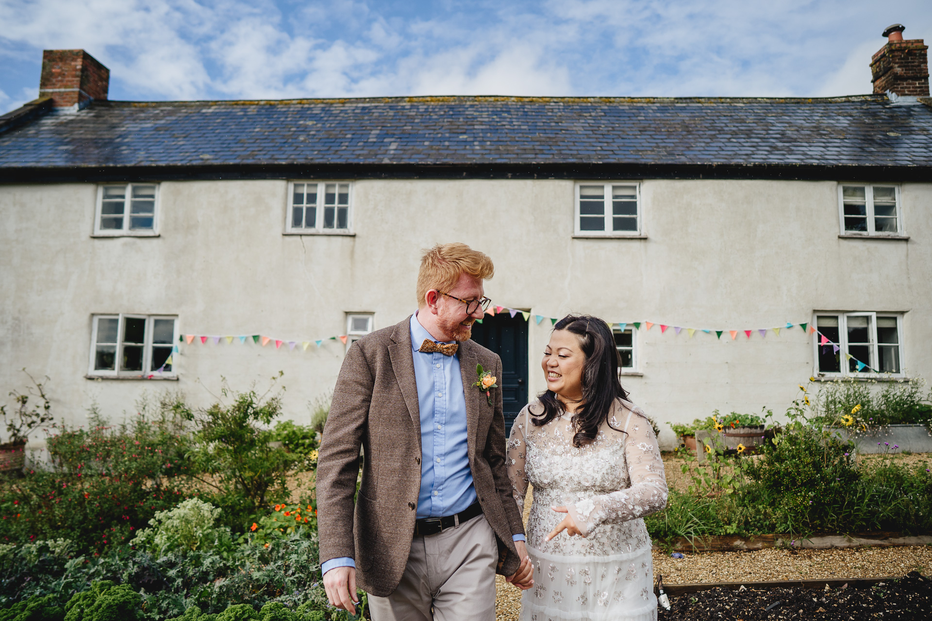 bride and groom smiling in front of river cottage farmhouse