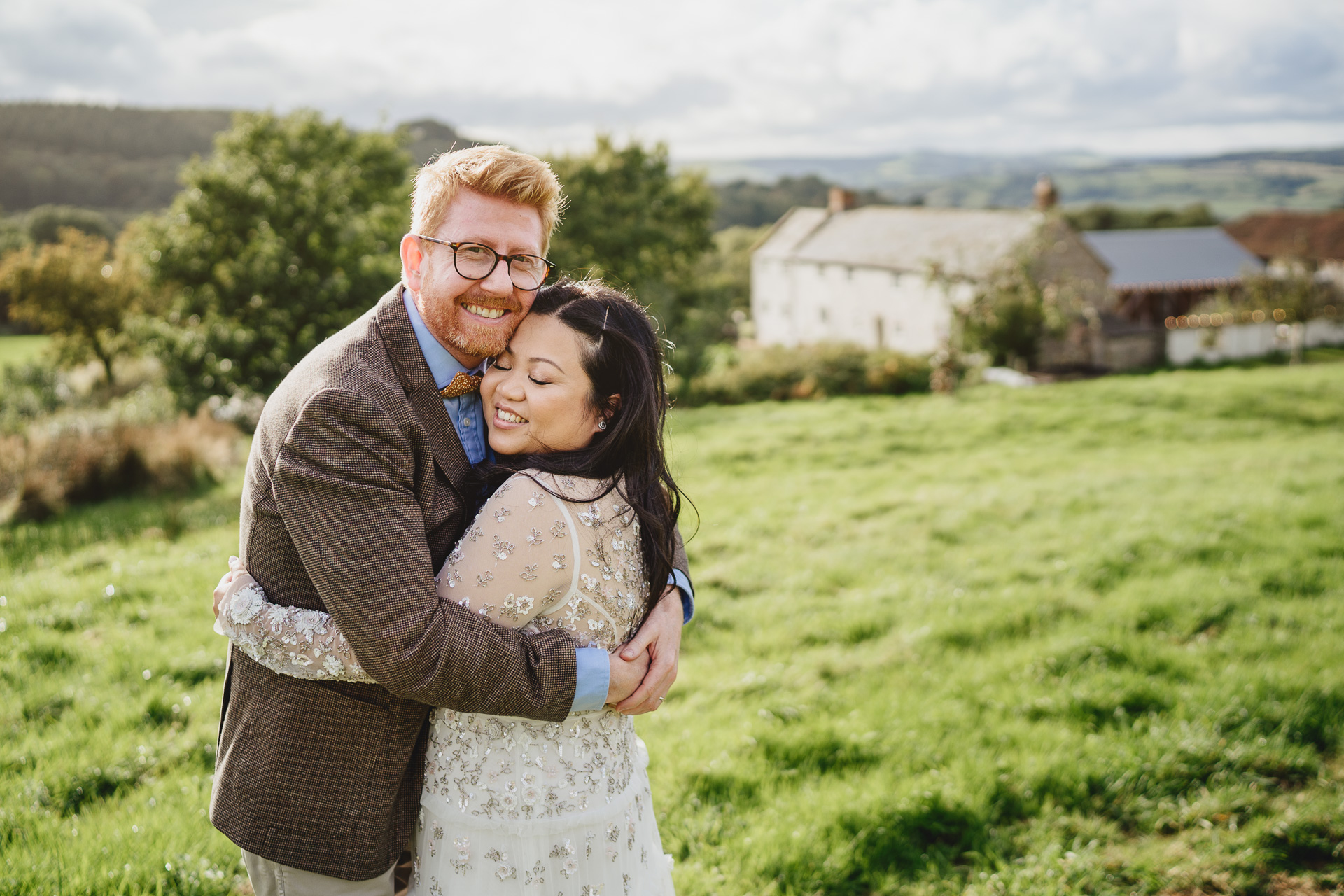 Bride and groom with river cottage behind them on an autumn wedding day