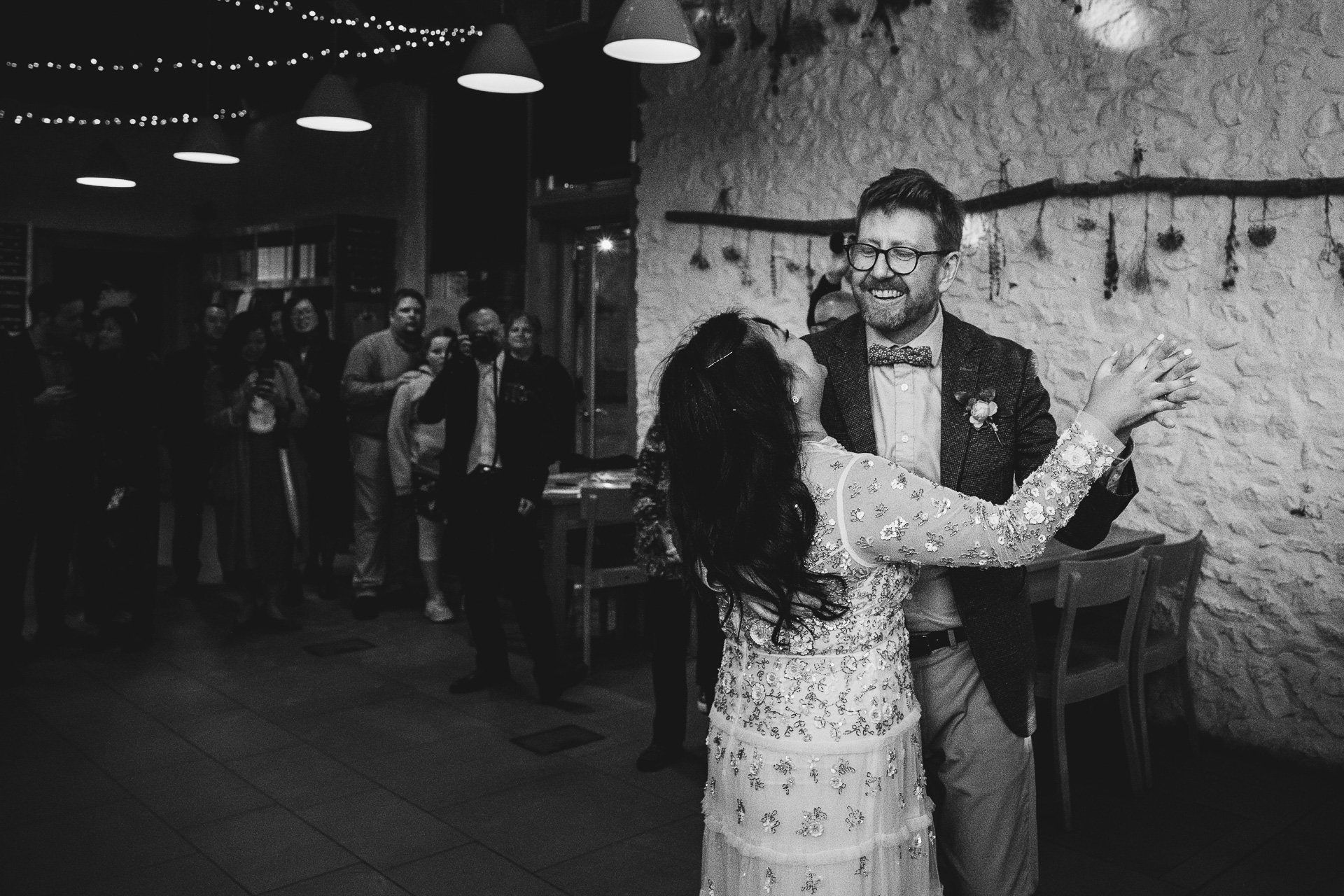 bride and groom dancing together with wedding guests watching