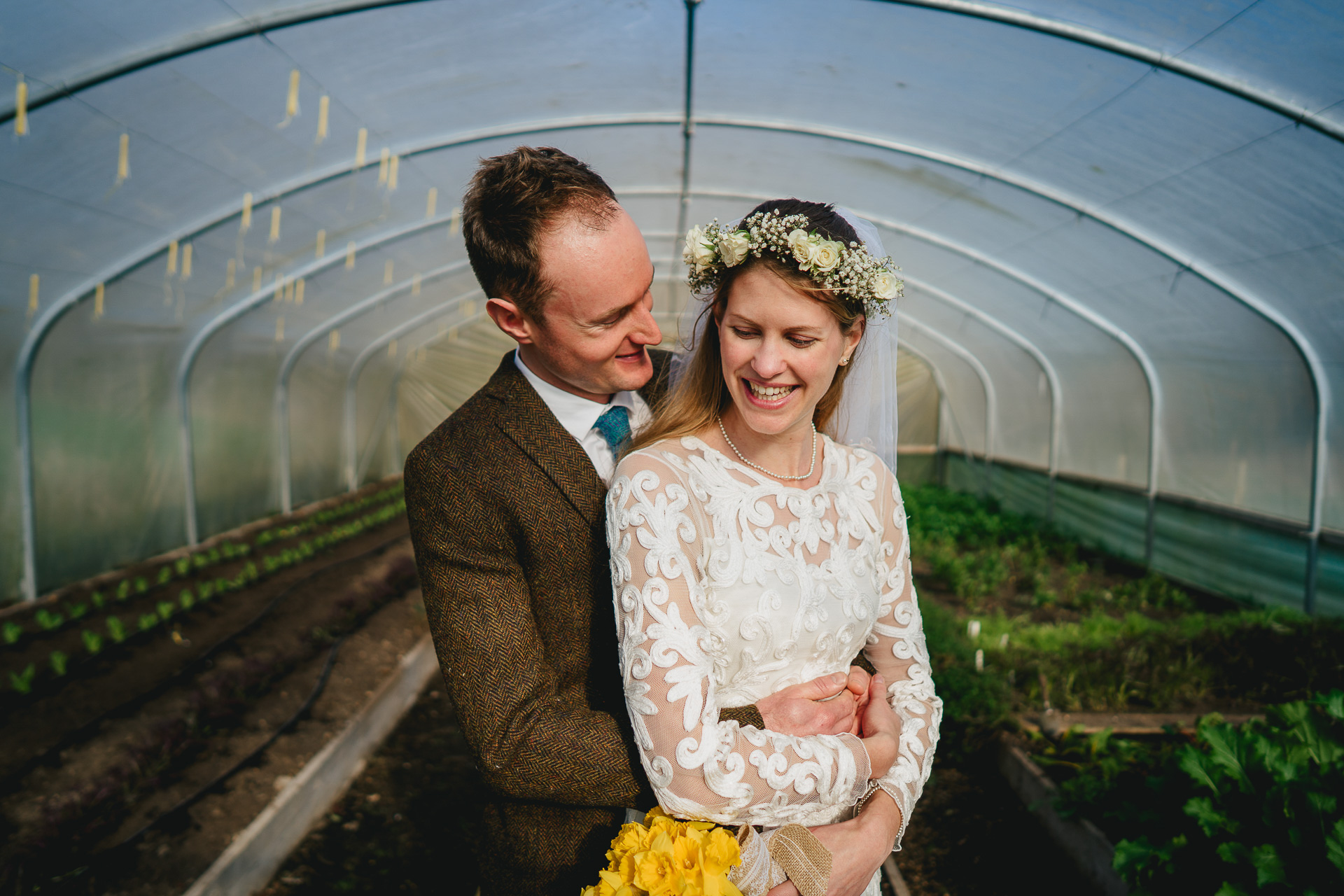 Bride and groom cuddling together in a poly tunnel