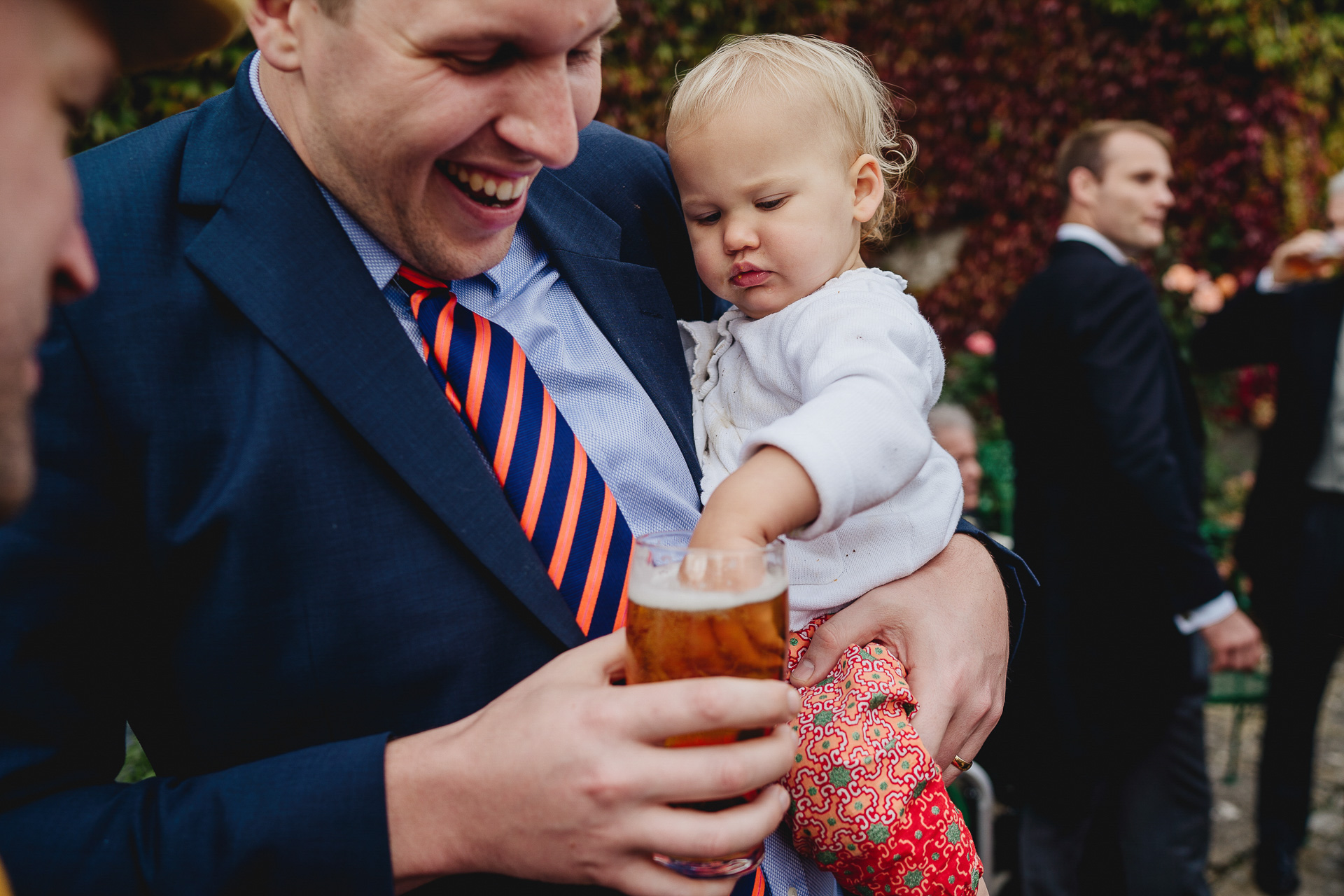 Baby with it's hand in a pint of beer