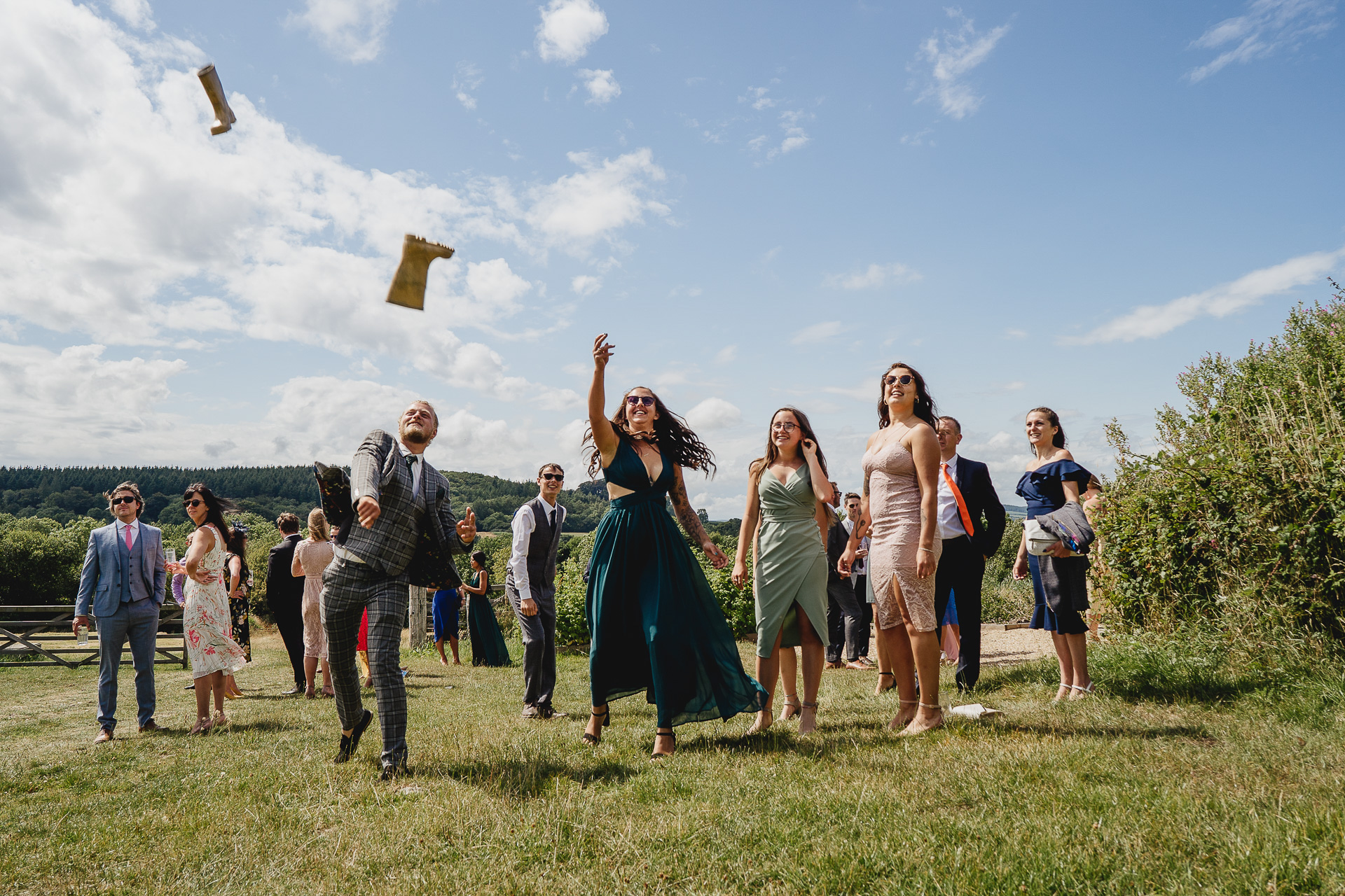 Wedding guests throwing wellies in a field