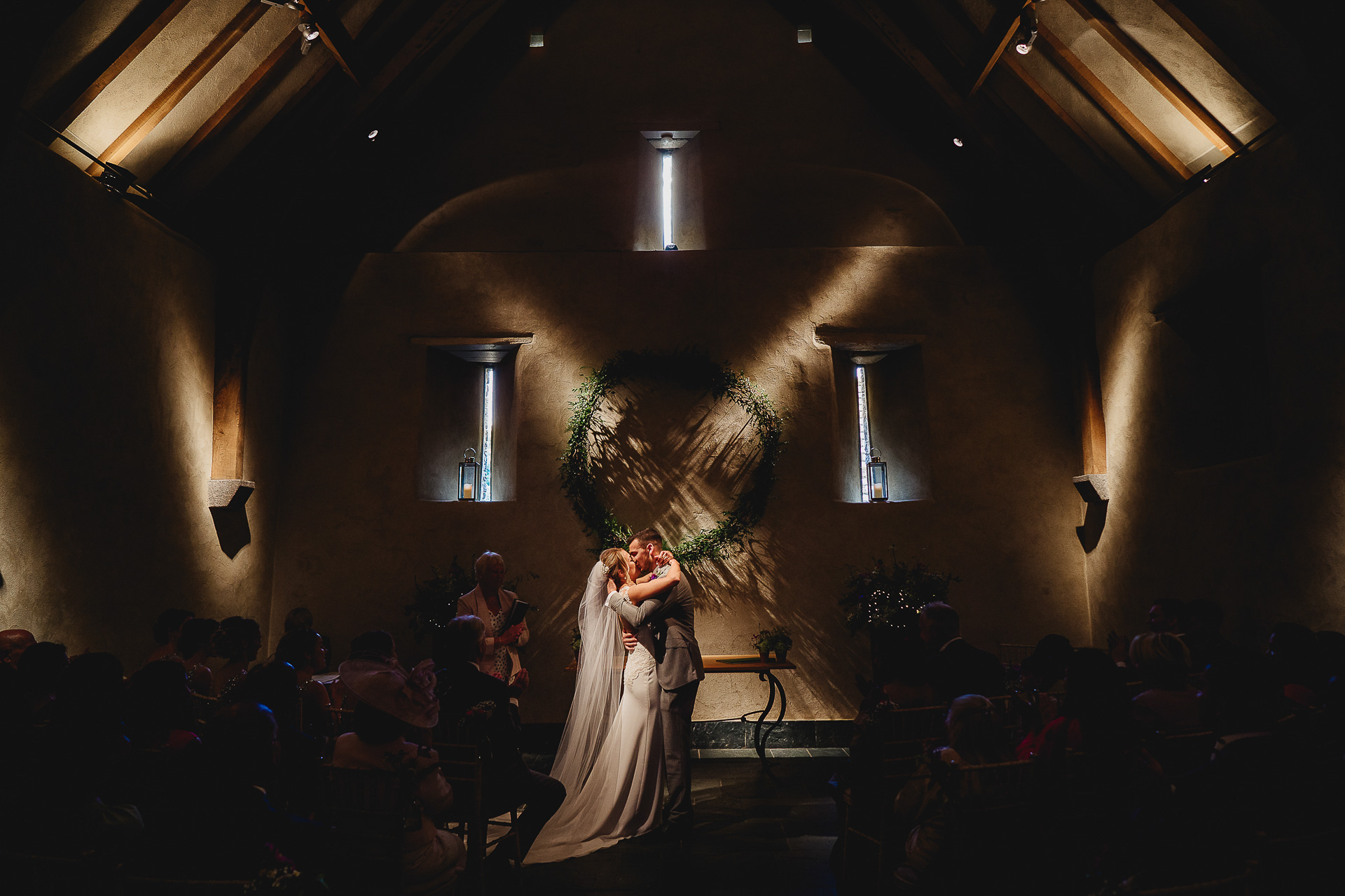 Bride and groom kissing in the Great Barn Devon