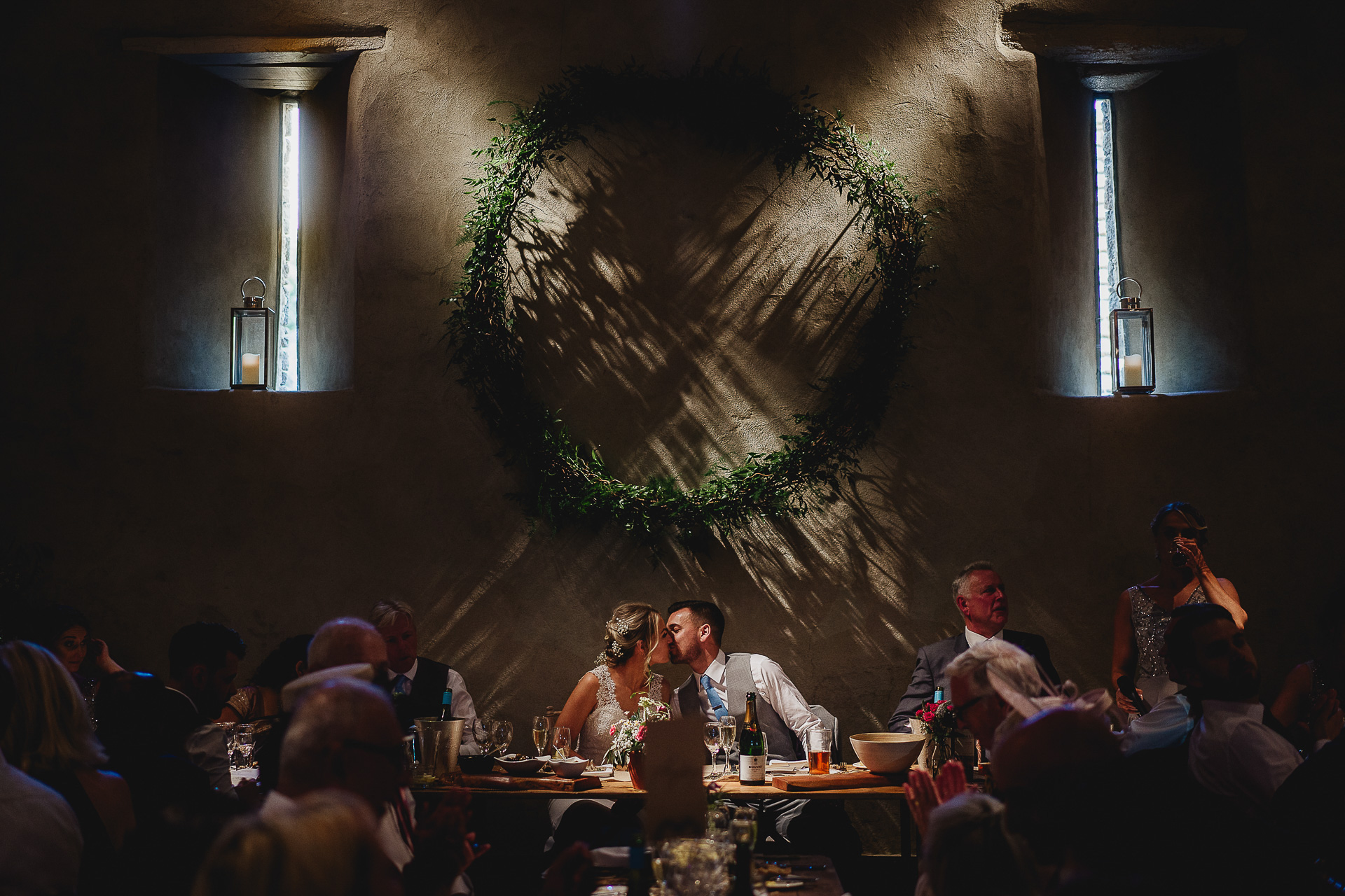 Bride and groom kissing at a table in a dark barn