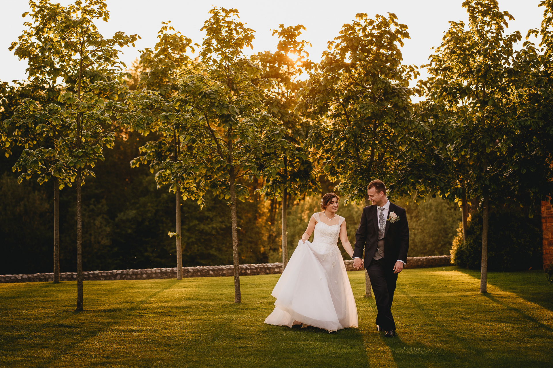 A bride and groom walking together in evening light