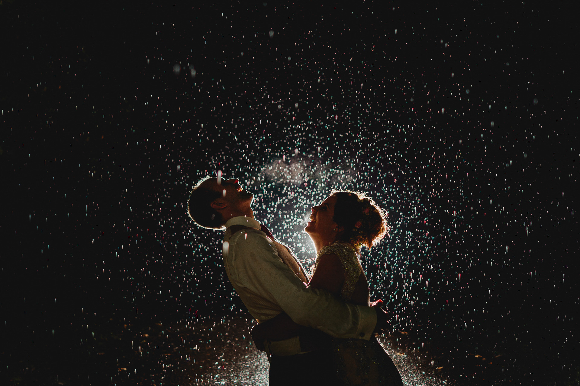 A bride and groom laughing together in the rain