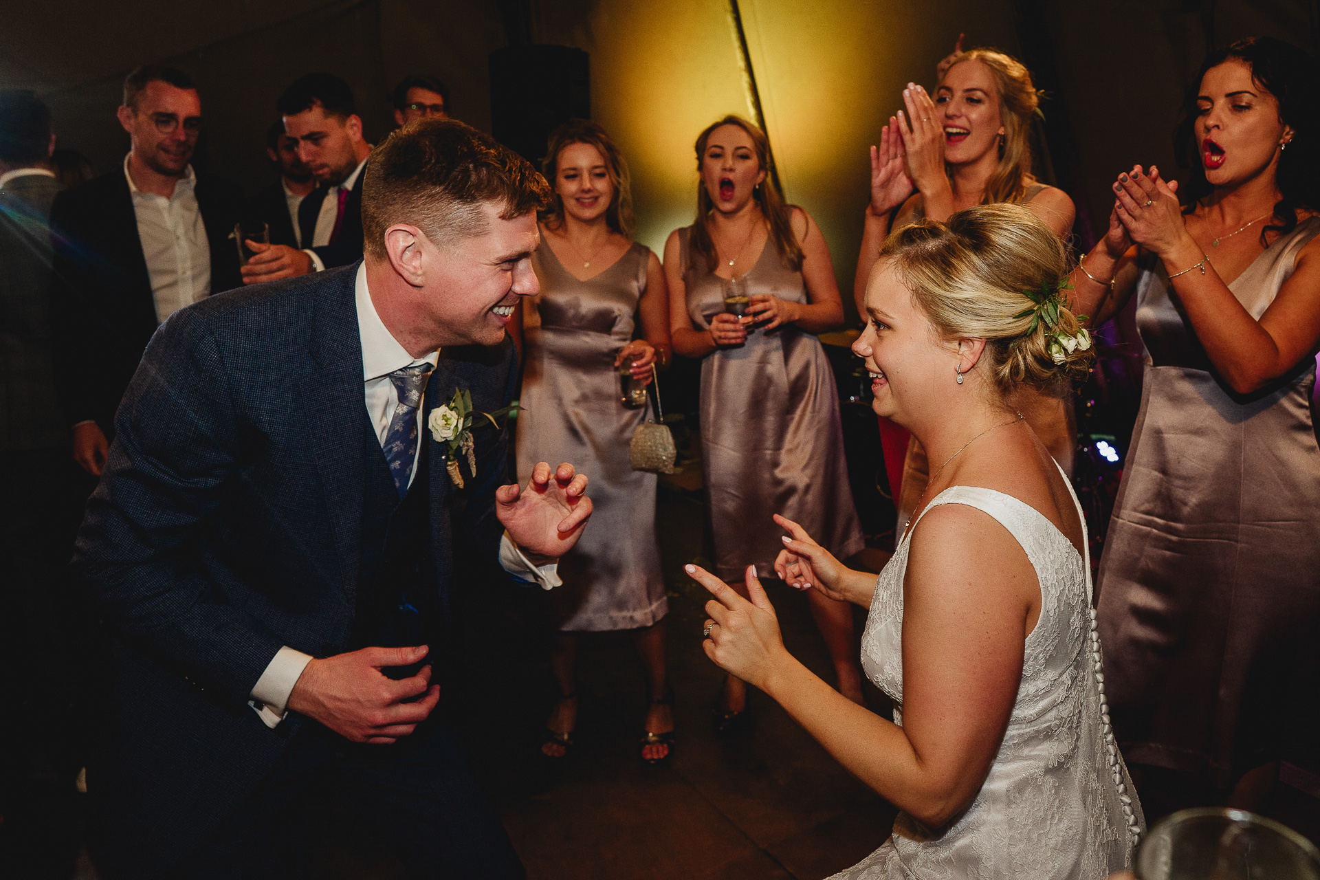 Bride and groom dancing together surrounded by clapping bridesmaids