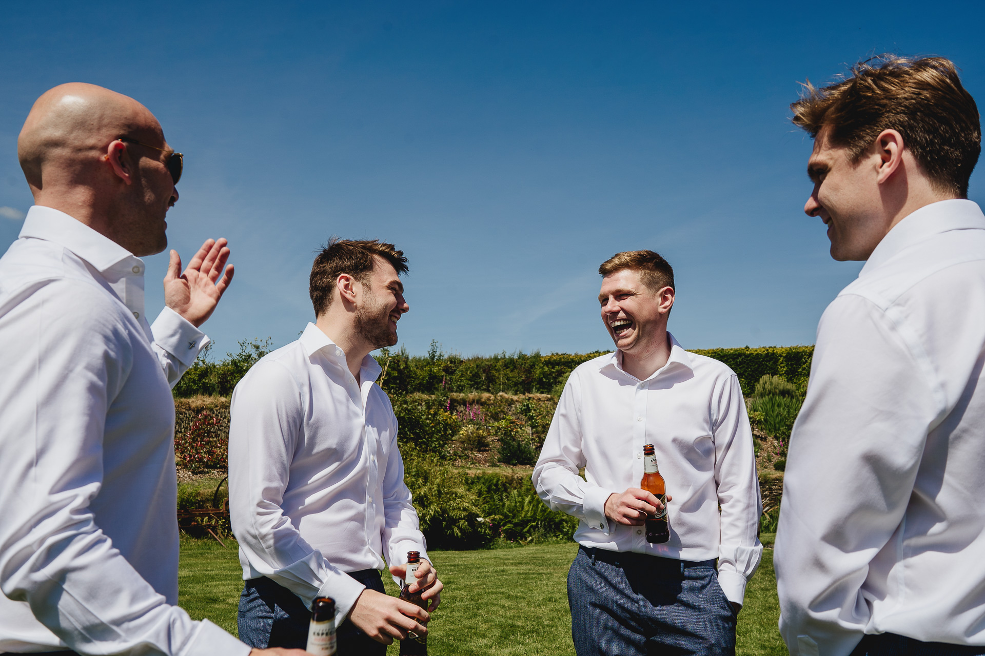 A group of men in white shirts laughing together