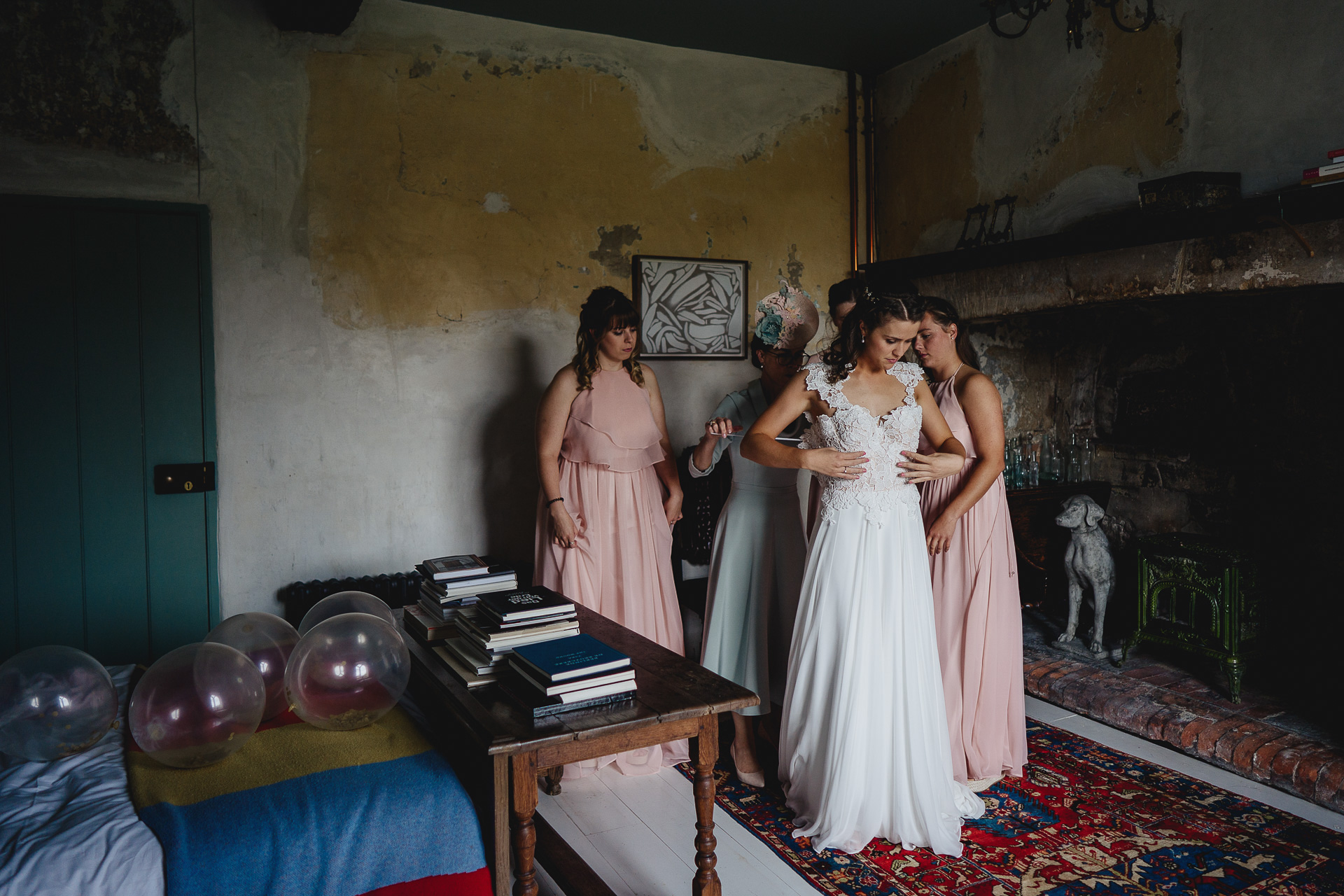 Bride with bridesmaids putting on a wedding dress
