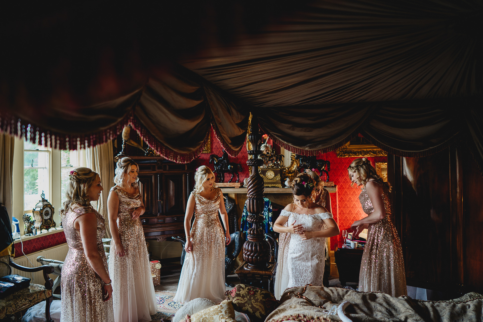 Bride and bridesmaids getting ready by a four poster bed
