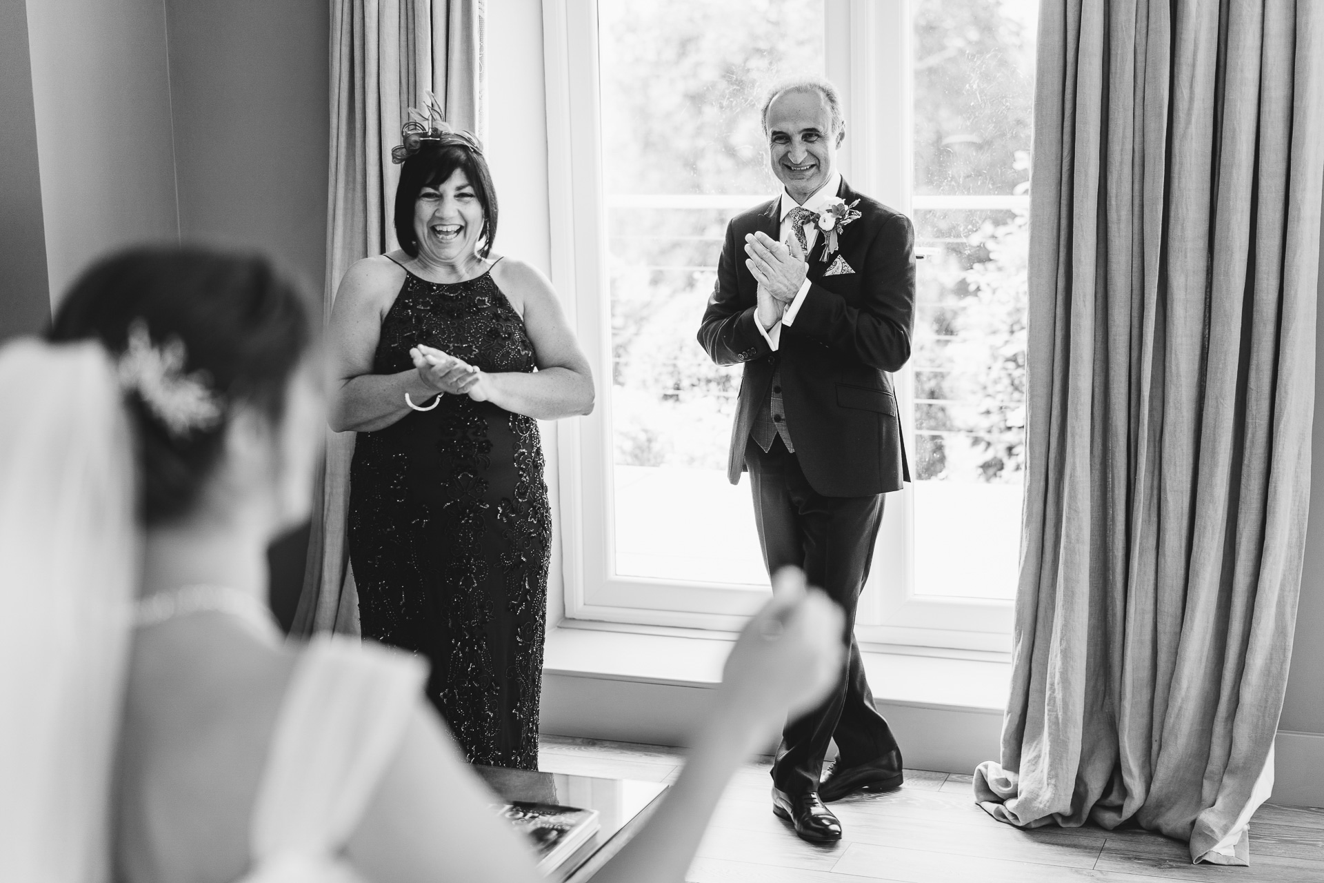 Parents of a bride clapping at her in wedding dress