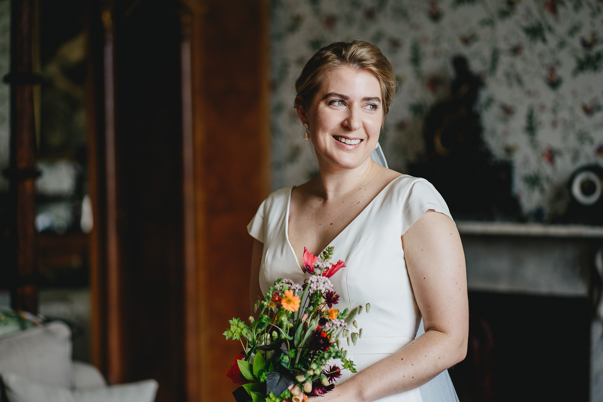 Bride with bouquet smiling in window light